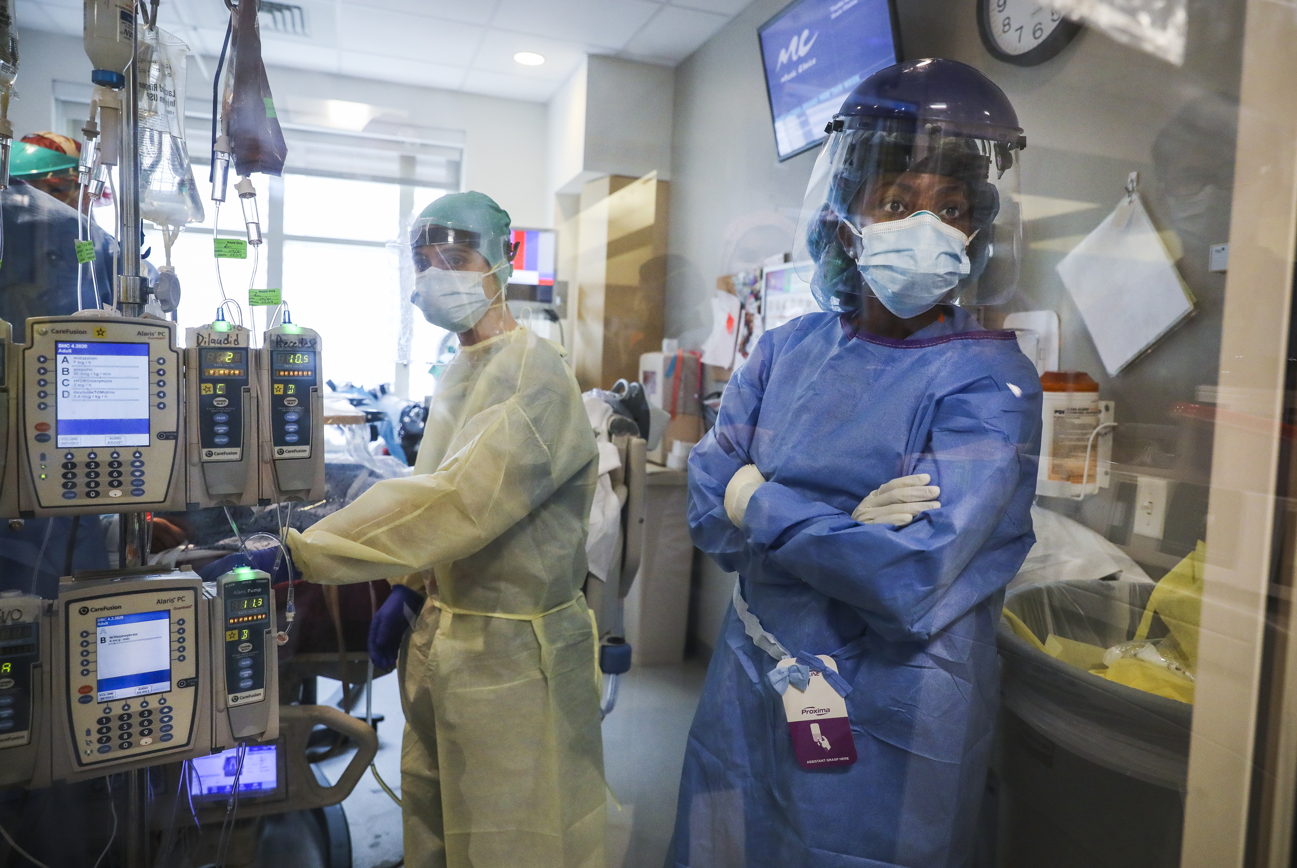 Nurse Kate Hartley (left) and Dr. Jacqueline Wulu waited for additional supplies before performing a tracheostomy on a COVID-19 patient in a Boston Medical Center ICU. To minimize the risk of coronavirus exposure, the team kept the doors closed and used a radio to communicate with those outside the room.