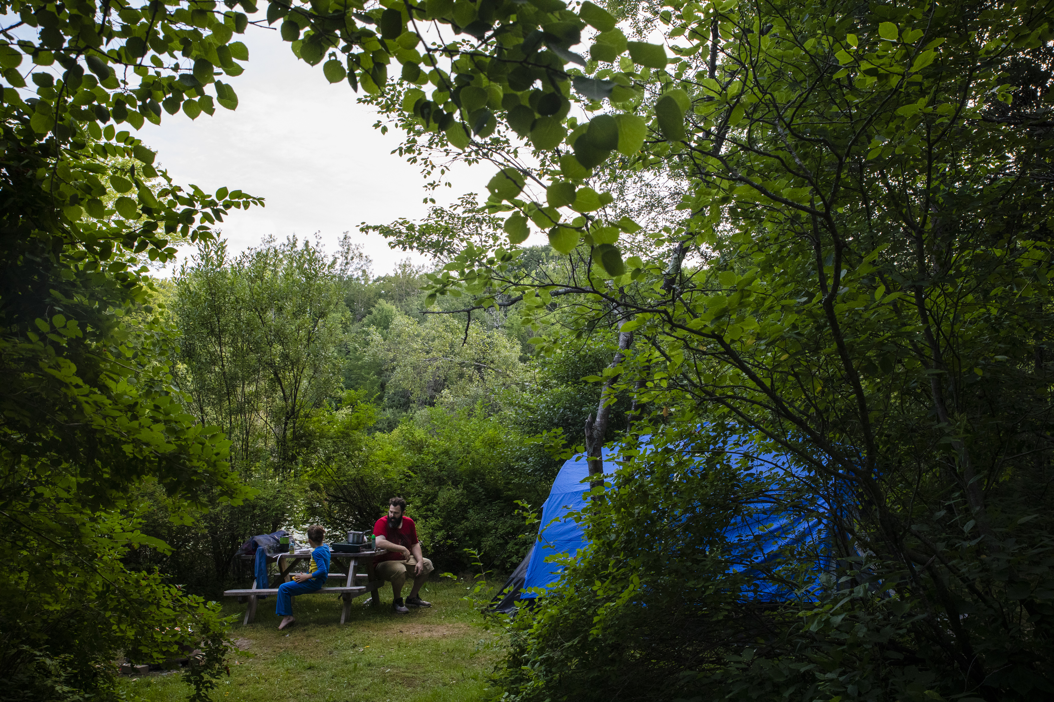 Patrick sat with his son Evan at their campsite. Surrounded by a pond and dense forest, the parents had to be abundantly cautious to ensure the children did not wander off.