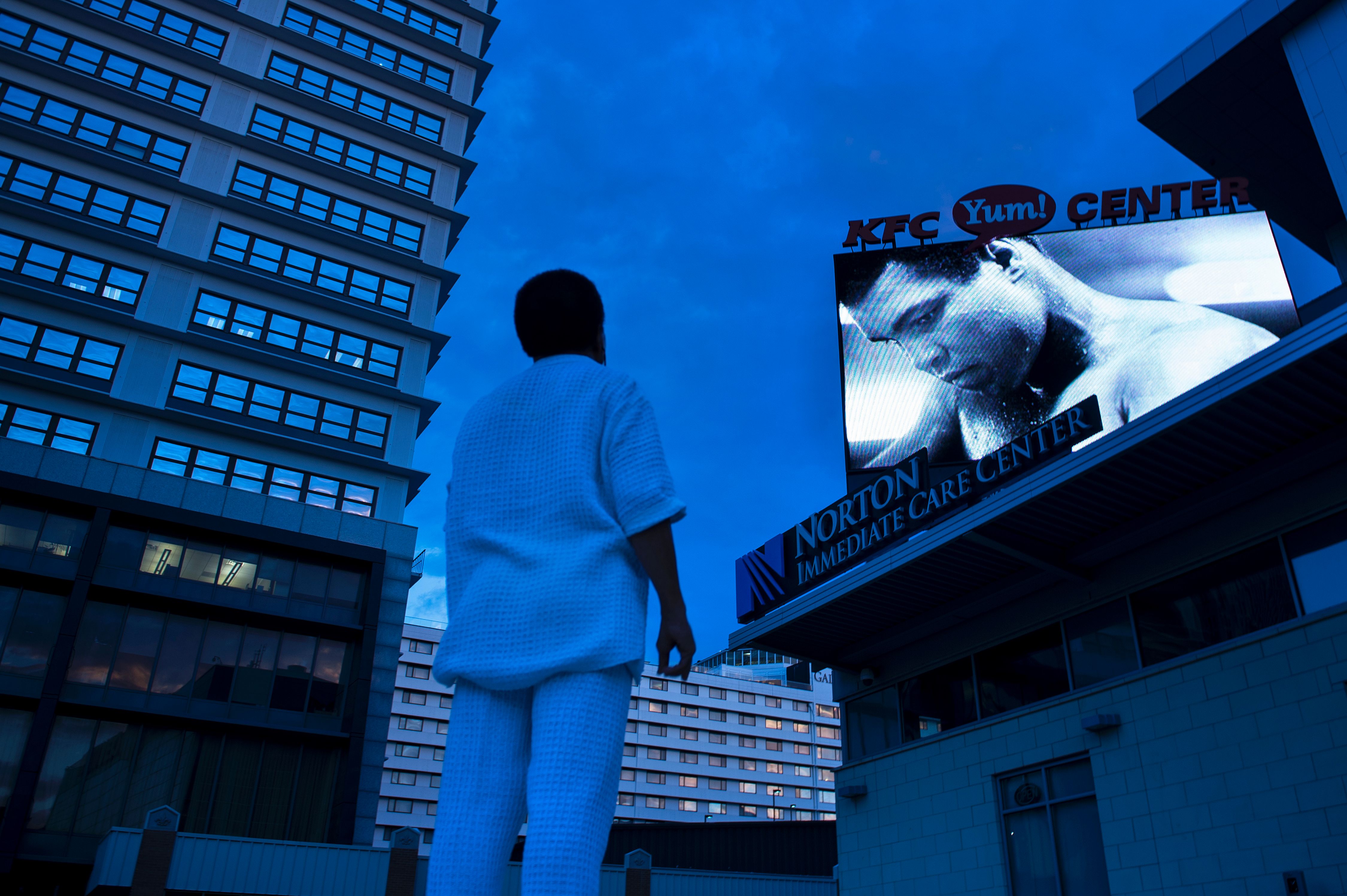A man watched a slideshow of photos of Muhammad Ali displayed on a screen outside the KFC Yum! Center in Louisville. An interfaith memorial service will be held Friday afternoon at the venue.