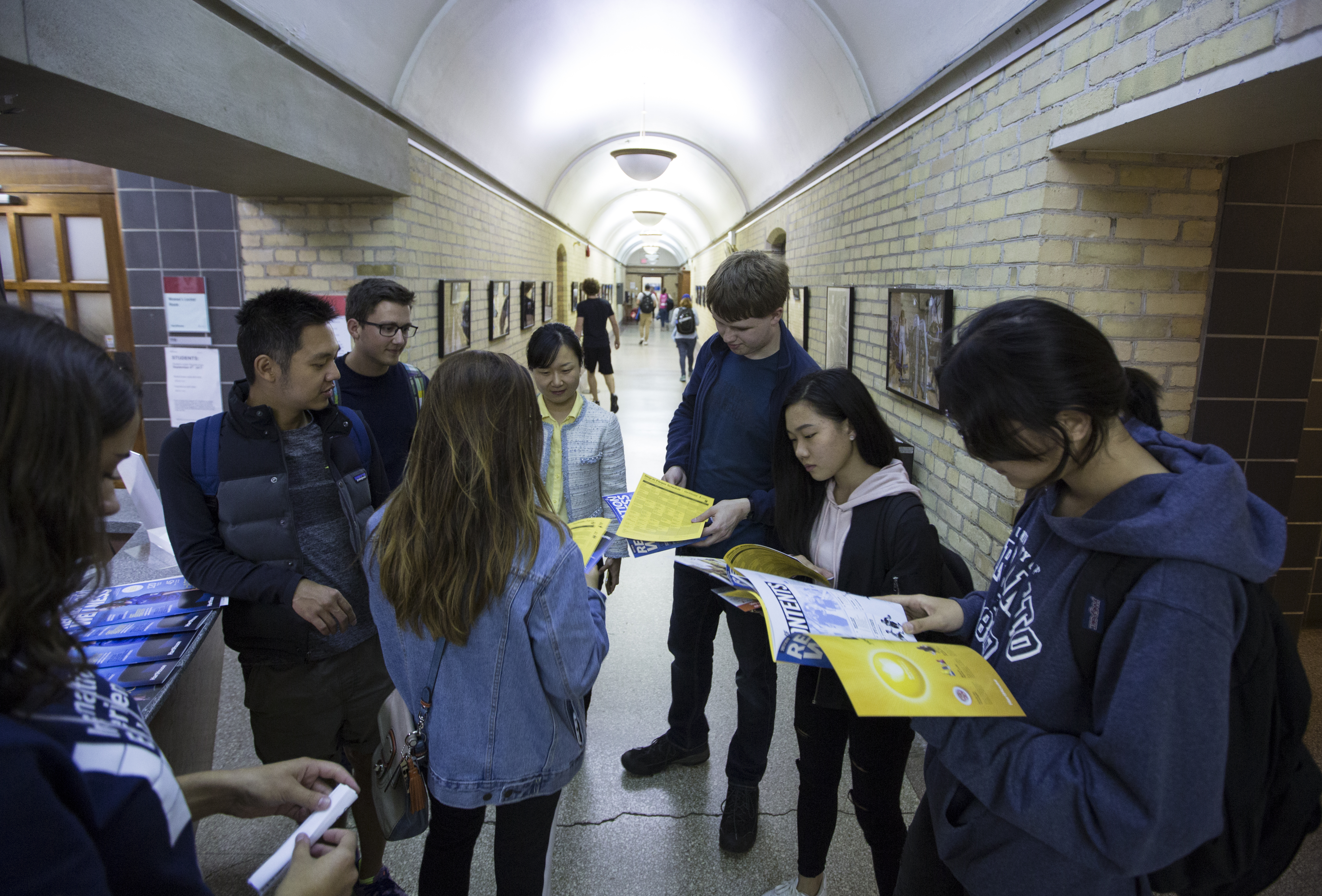 A group of foreign students browsed a brochure while touring the University of Toronto campus.