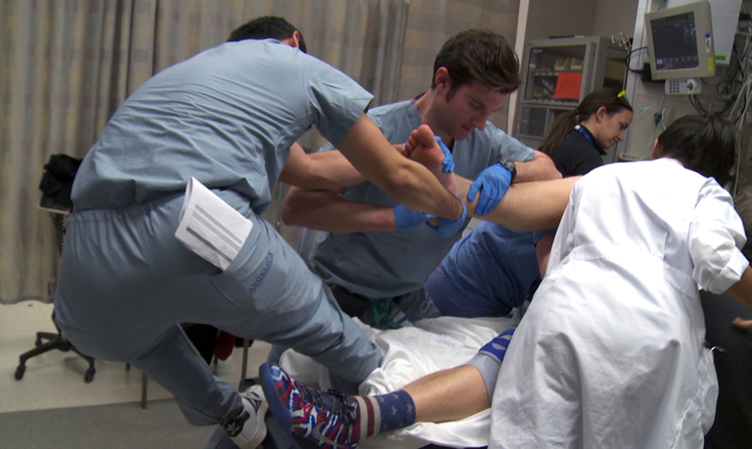 Dr. Erik Newman (center), an orthopedic surgery resident, helps yank a dislocated ankle back into position at Brigham and Women's Hospital.
