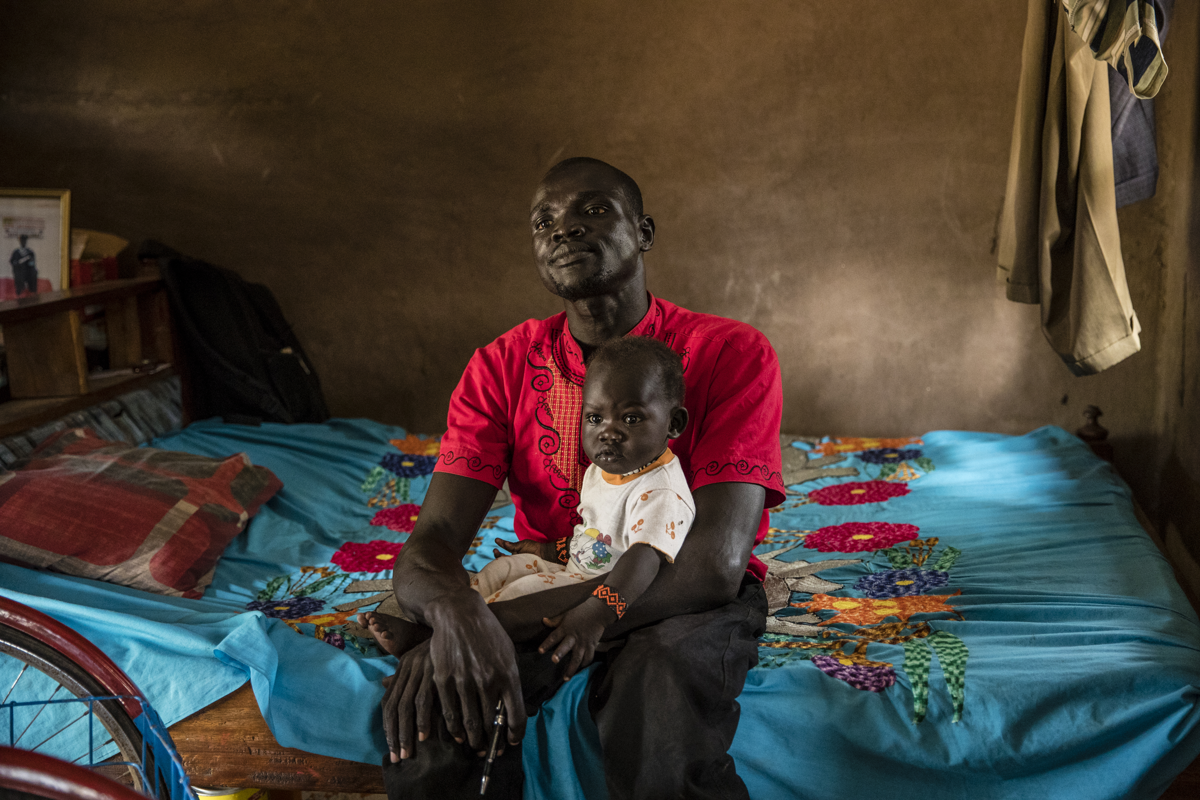 Bol Daniel Maduk, who contracted polio as a child, held his infant daughter on his lap in the compound where he lives in the UNHCR refugee camp in Kakuma.