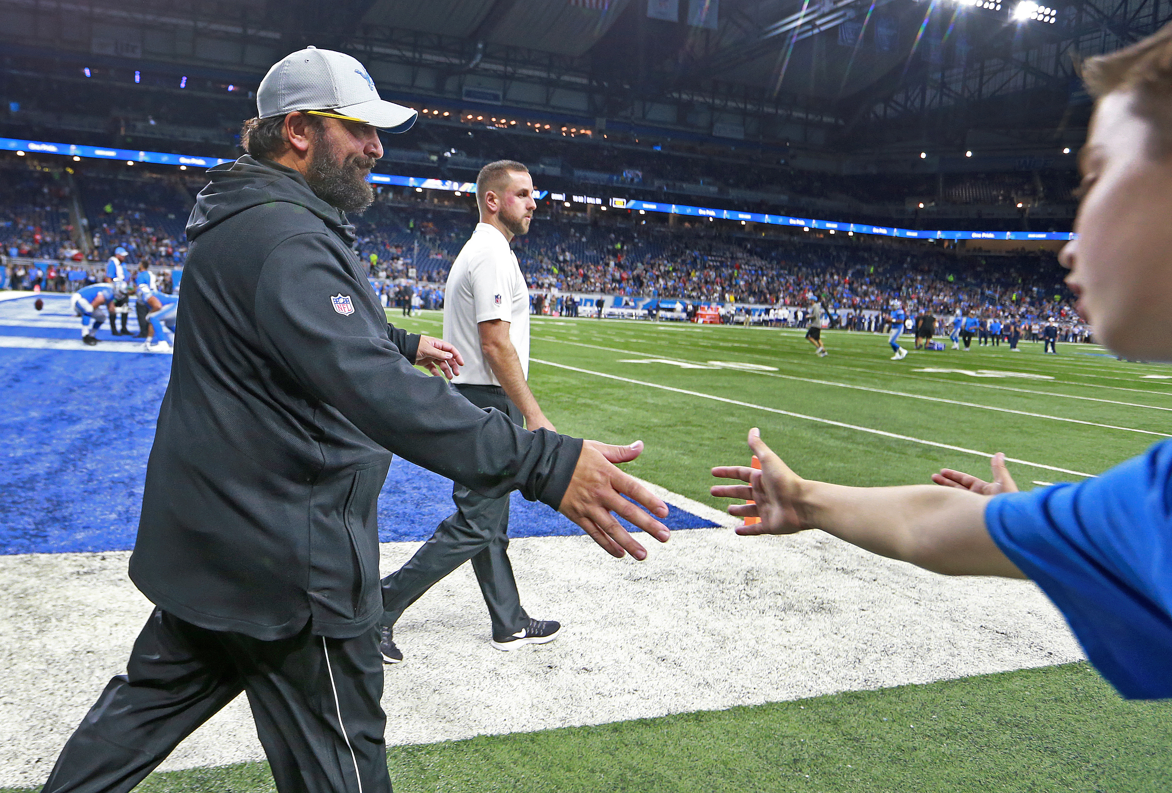 Matt Patricia gives a hand to a young fan as he comes onto the field for pregame warmups.