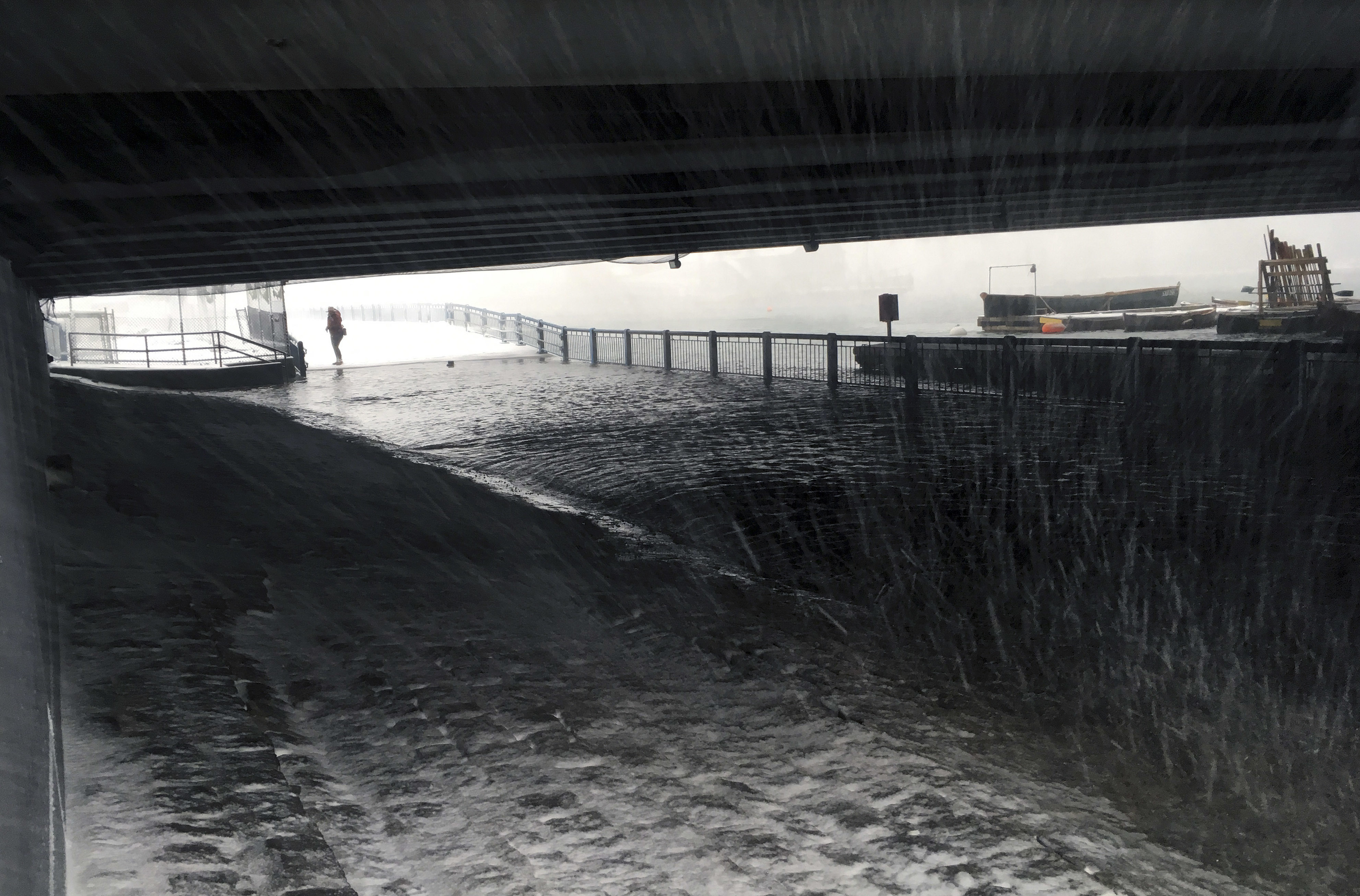 Water flooded a pedestrian walkway along the Fort Point Channel under the Seaport Boulevard bridge.