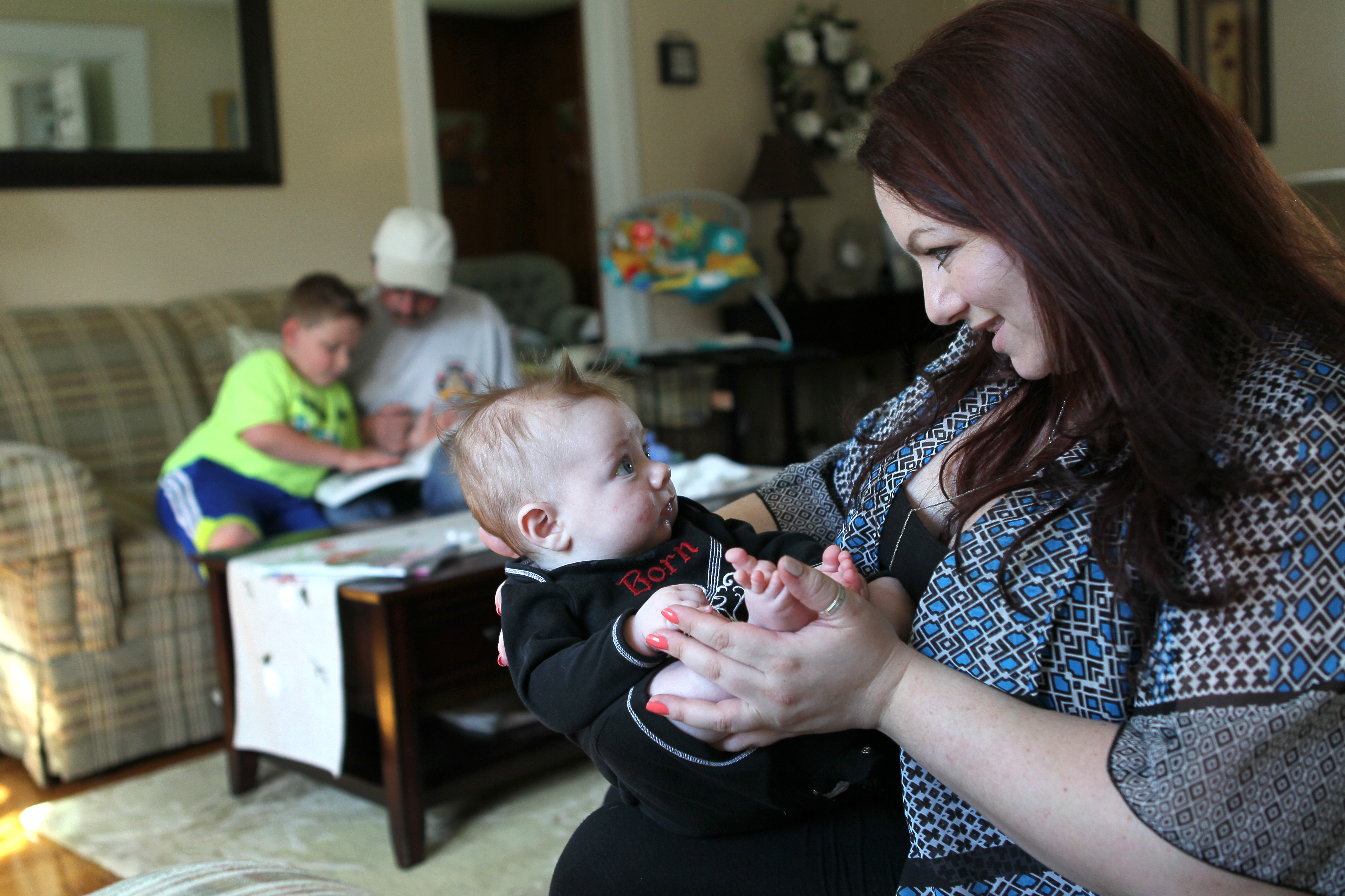 Michelle Frigon talked to Charlie, 4 months, as her son William, 7, read with his grandfather.