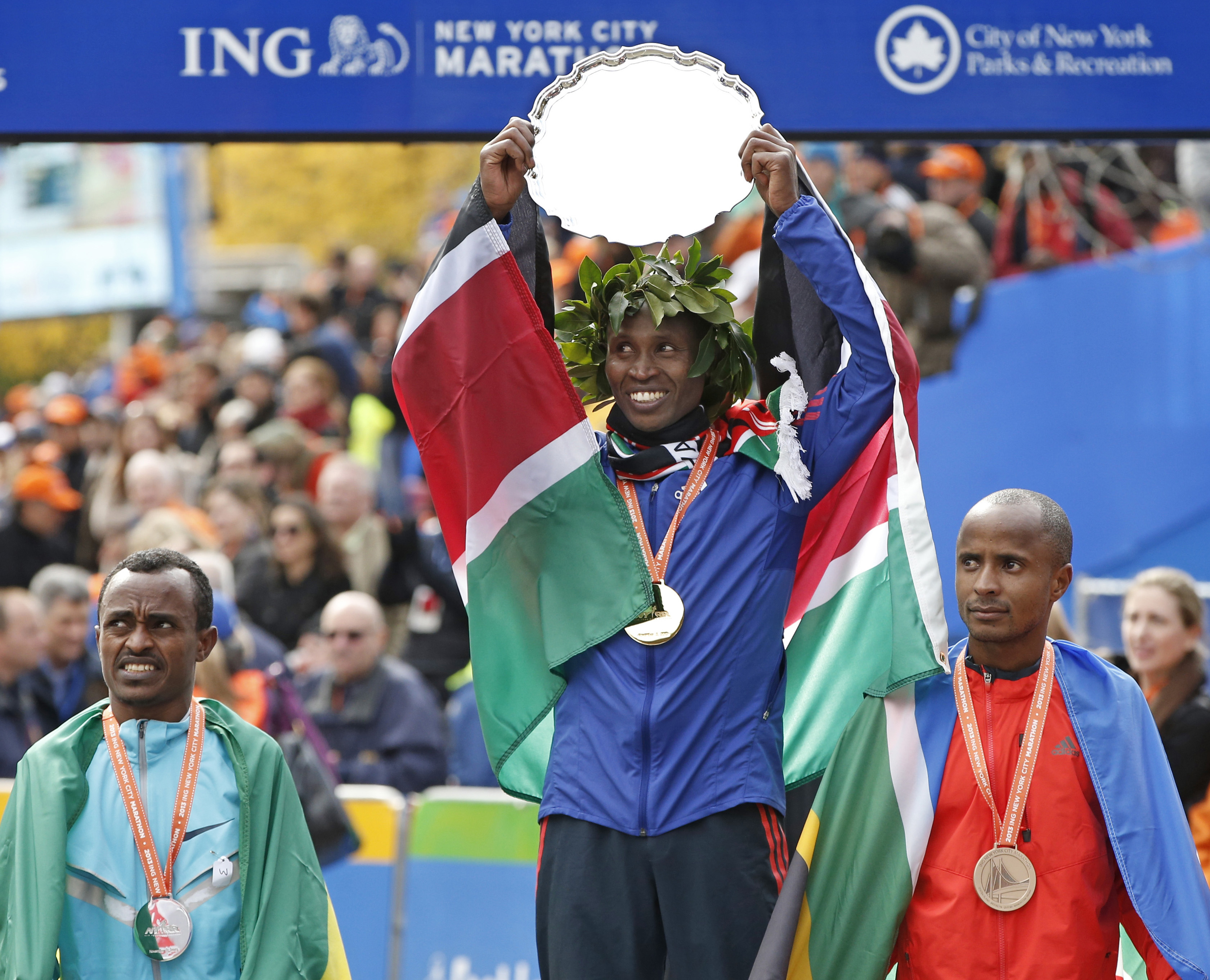 Geoffrey Mutai holds up the hardware for winning the New York City Marathon, which wasn’t run last year.