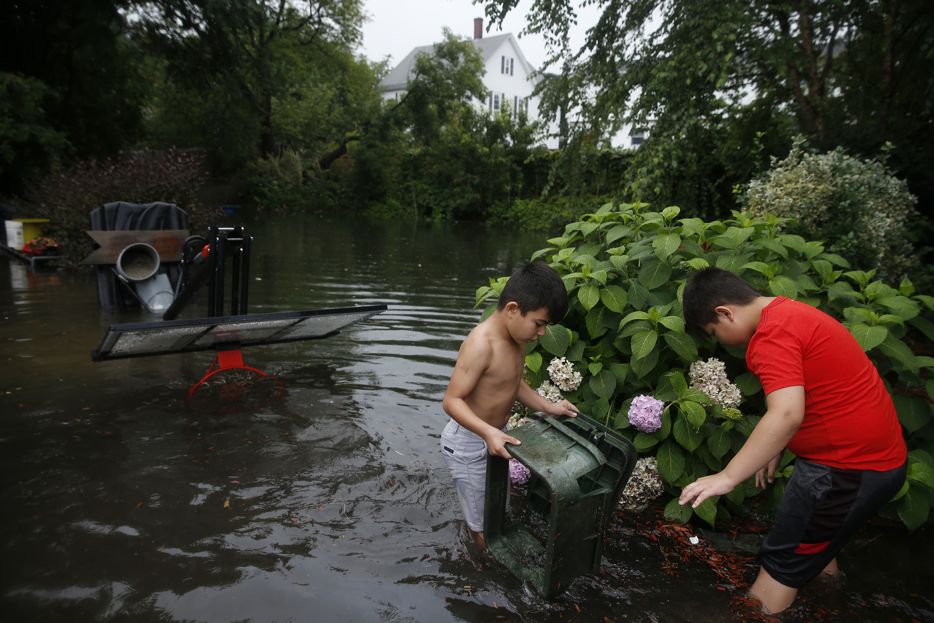 Angel Cardenas (left), 7, of Lynn, and his brother Chris, 10, picked up a chair that they found in the flood waters surrounding their home.