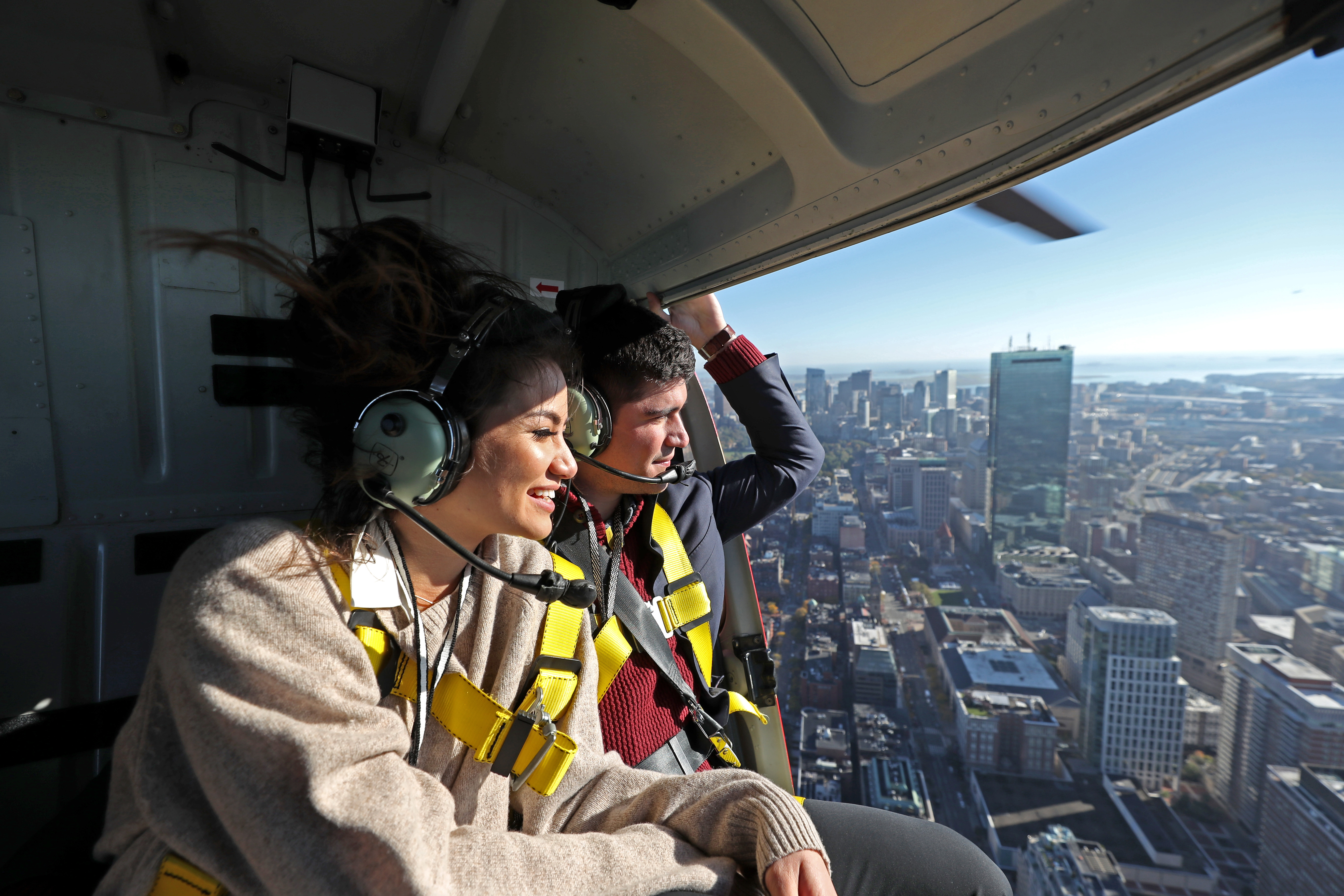 Caila Quinn and Nick Burrello in safety harnesses on their 30-minute doors-off helicopter tour of Boston.