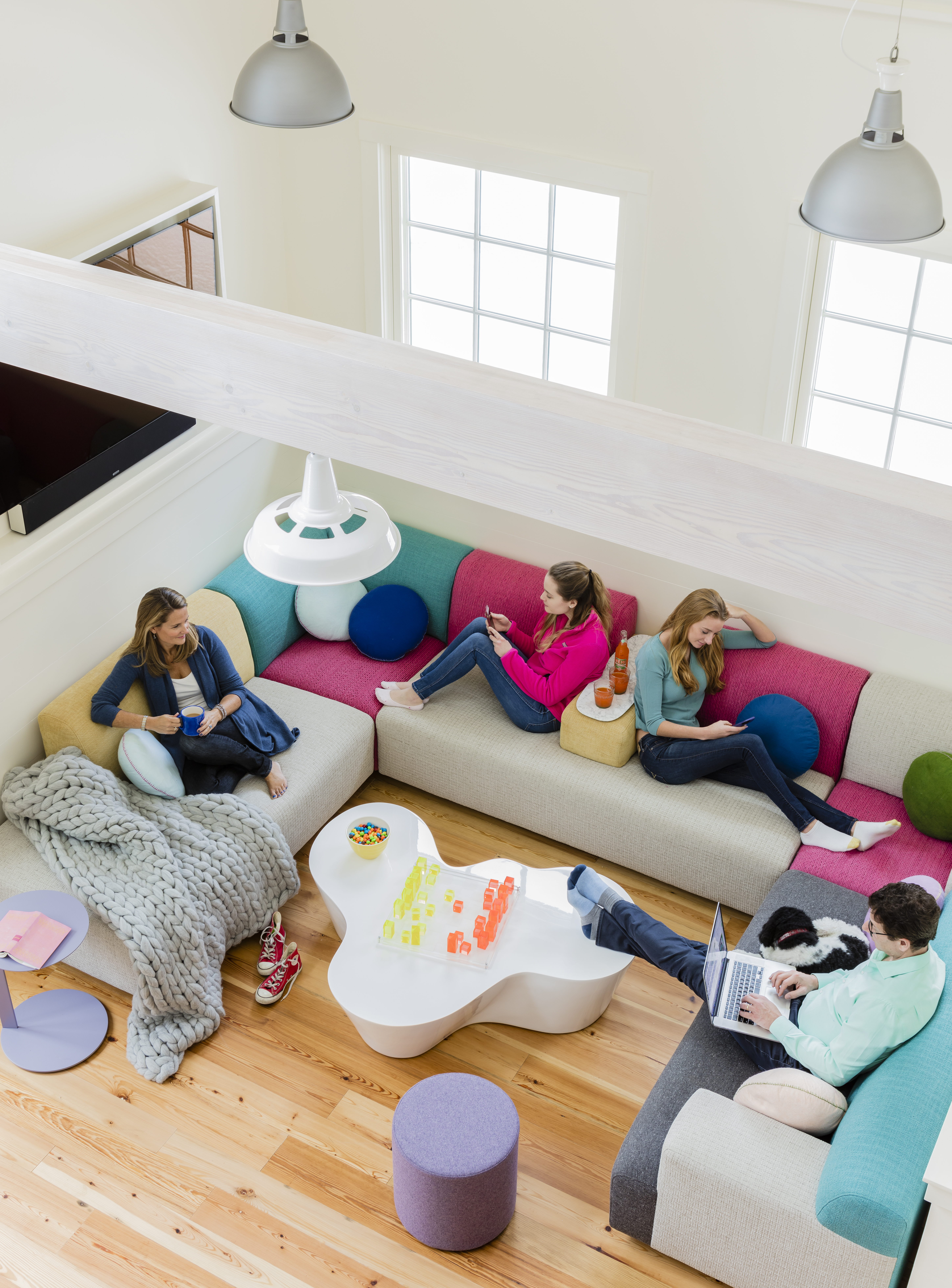 Amy and Jeff Glass, eldest child Lindsey, and her best friend, Katherine Cook (in pink), hang out on the custom sofa designed by Kate Maloney Albiani’s firm, KMID, and made by Partners in Design of Newton.