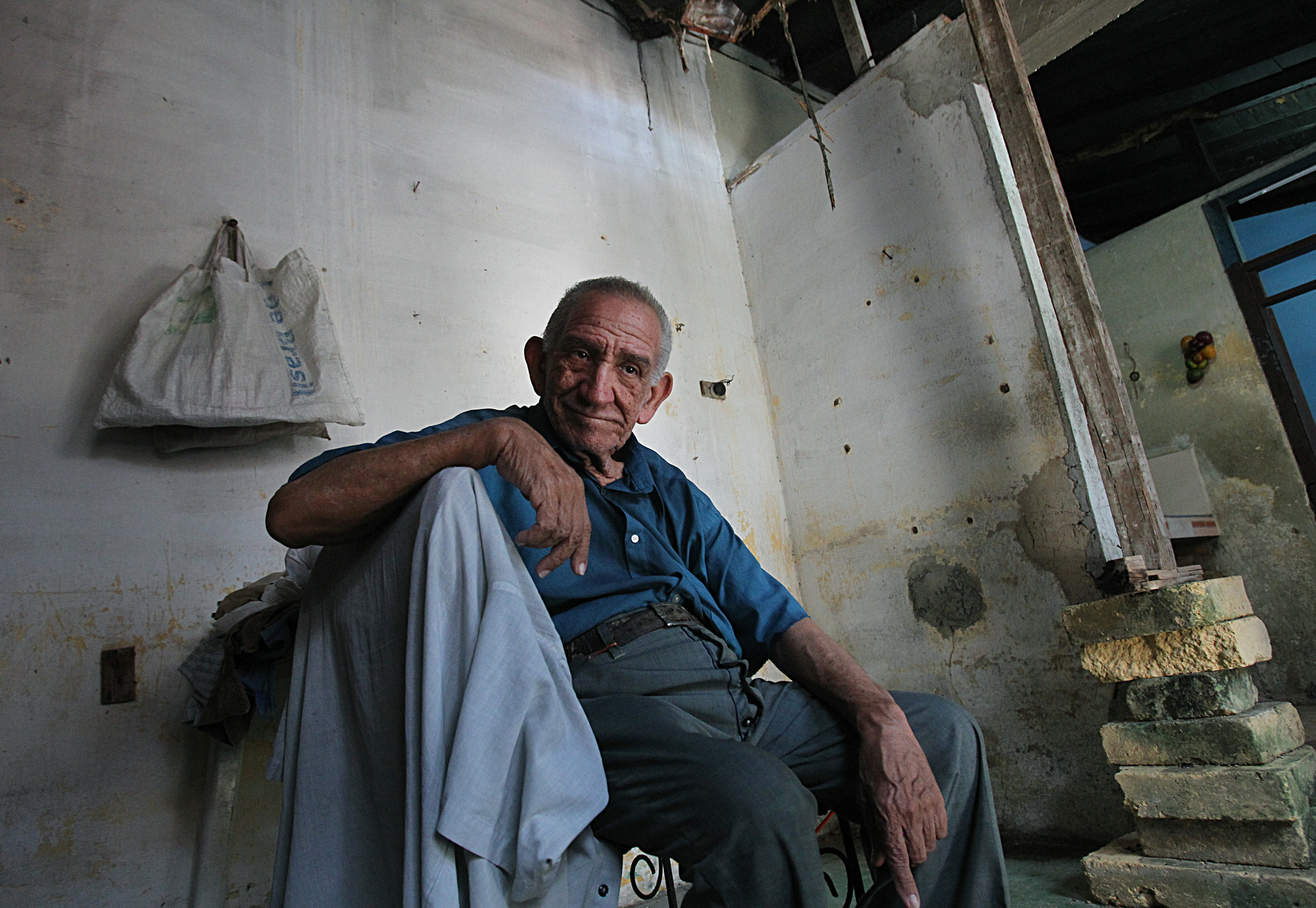 Raoul Zapata Bajo, 77, and his brother live in a house with a collapsed ceiling. It is being held up by uneven bricks and a temporary pole.