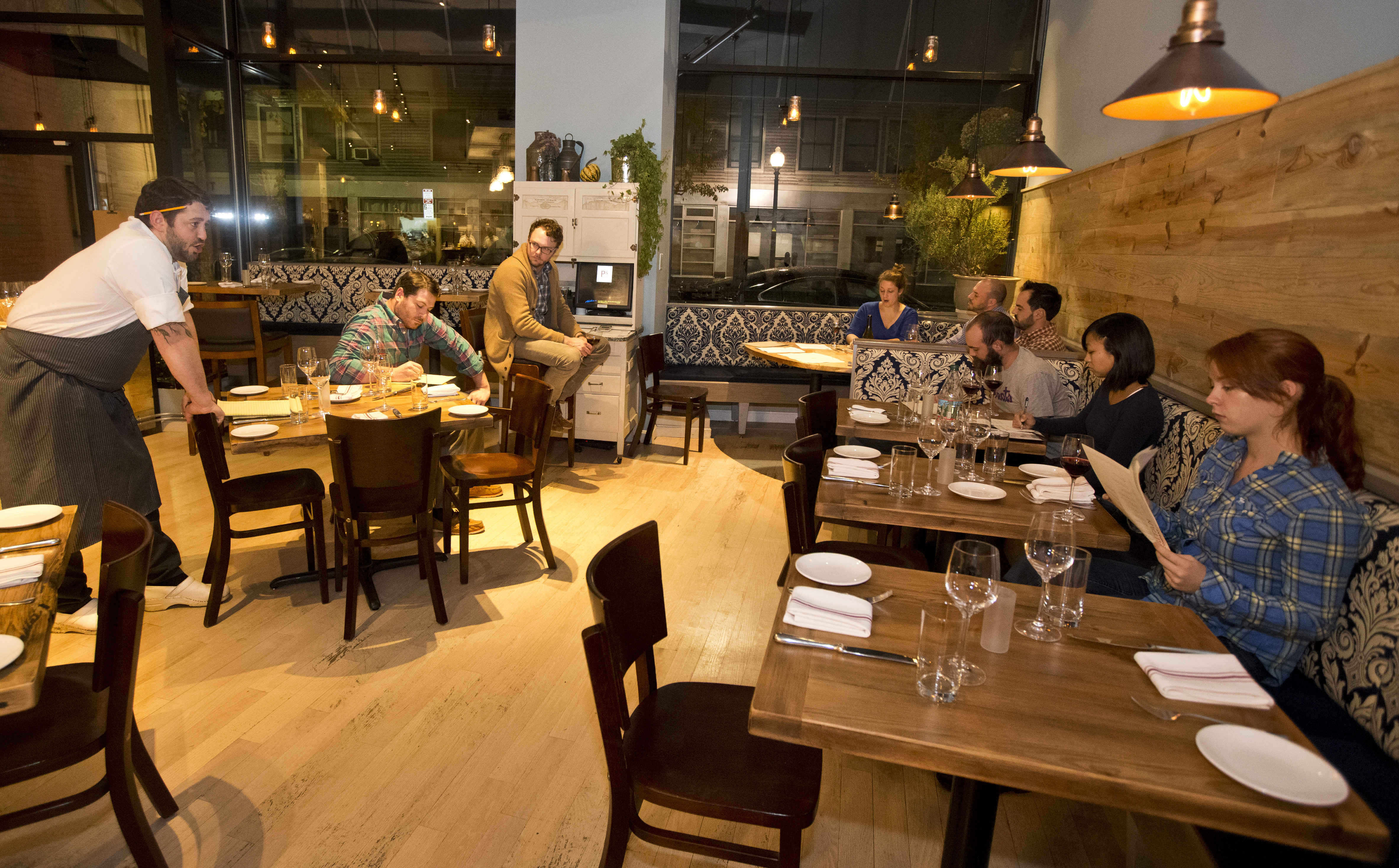 Will Gilson (left), directed a staff meeting at Puritan & Company. Many cooks he has interviewed are either seeking a second part-time job or are culinary school graduates expecting more pay than what the restaurant offers.