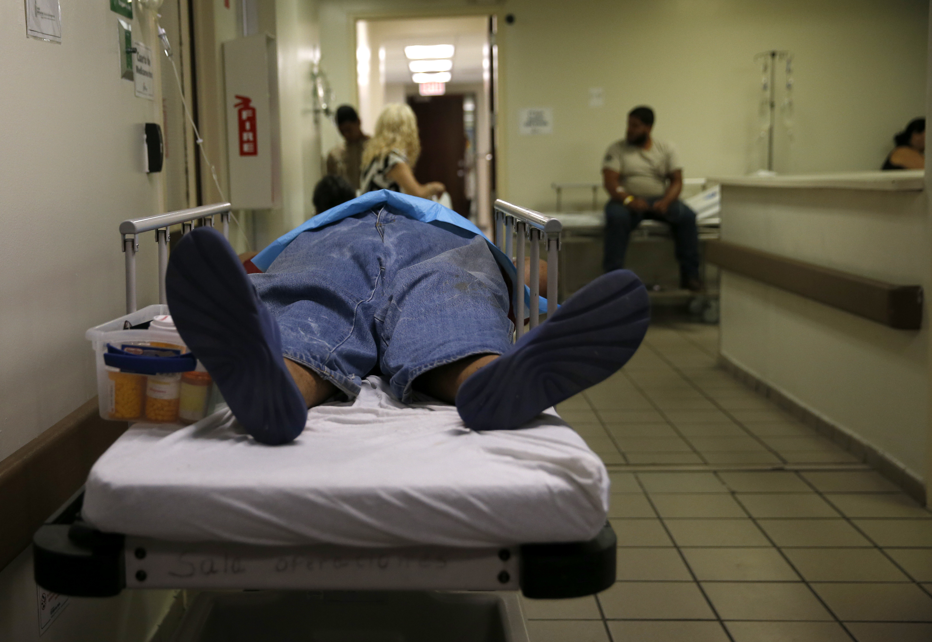A patient lay in a hospital bed in the hallway inside the emergency room at HIMA San Pablo Hospital in Caguas.