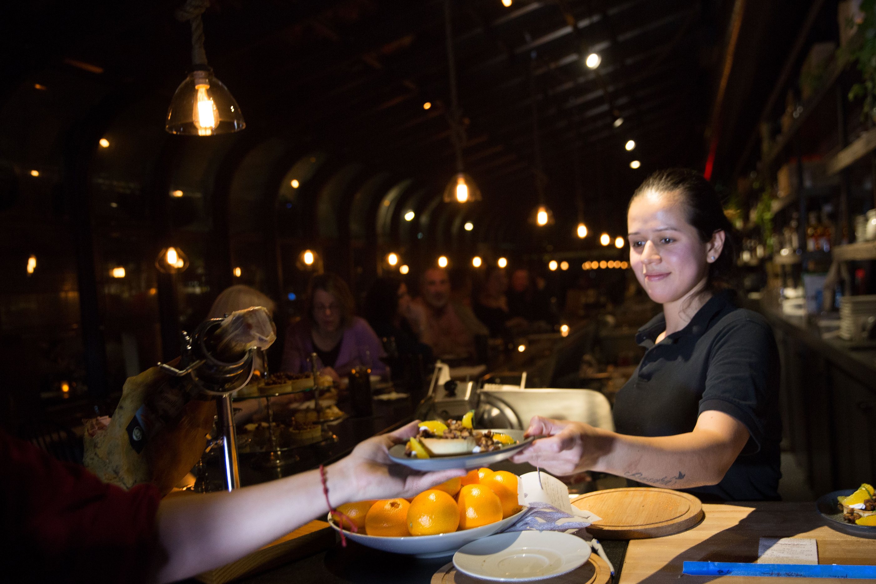 Cook Keara Garcia passes a dish to a server.