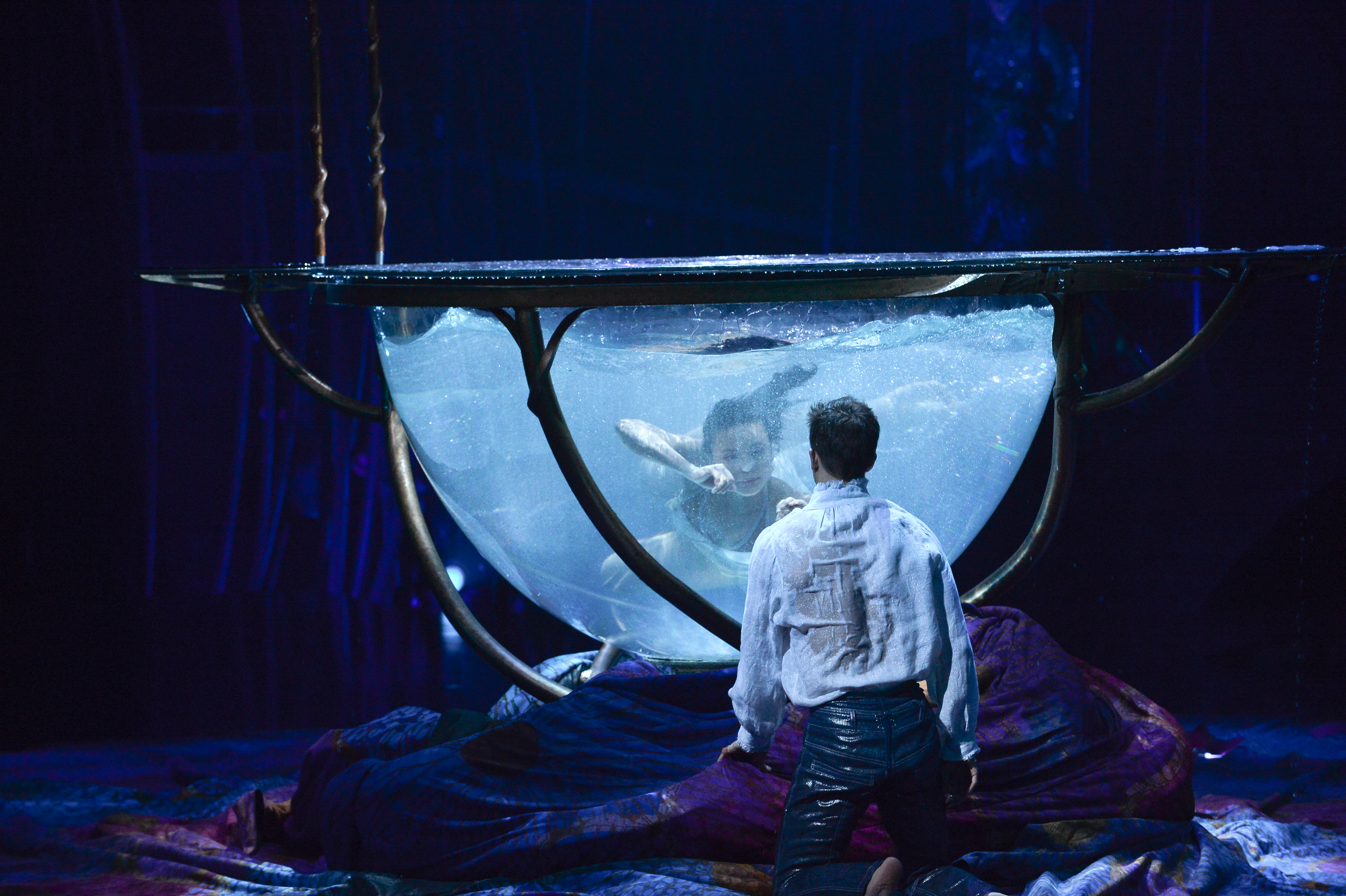 A Cirque cast member immerses herself in a large water bowl.