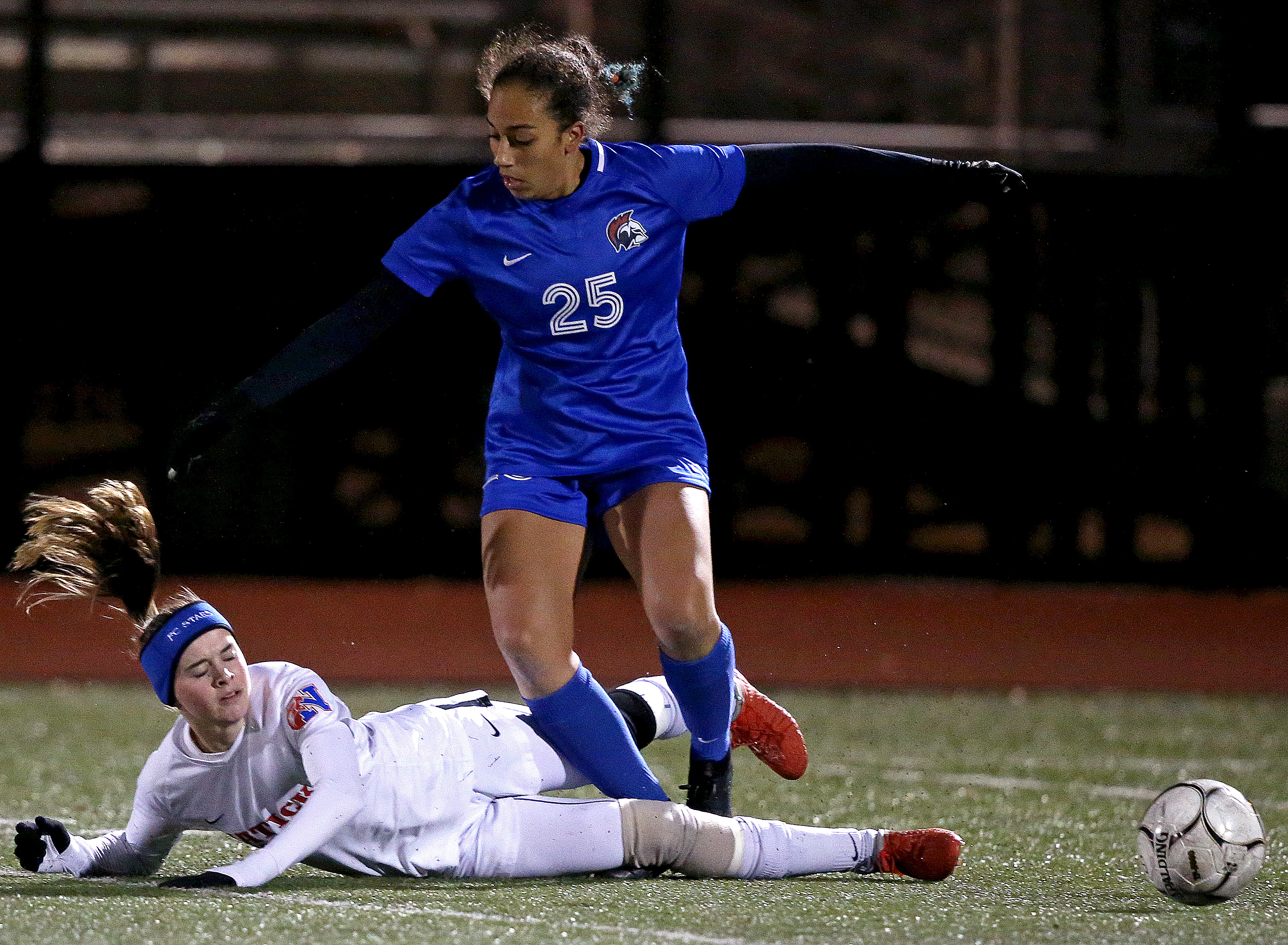 Natick's Abigail Gerdes (3) makes a sliding tackle of Brookline's Lindsey Mahoney (25) in the D1 girls' soccer state semifinals at Manning Field in Lynn.