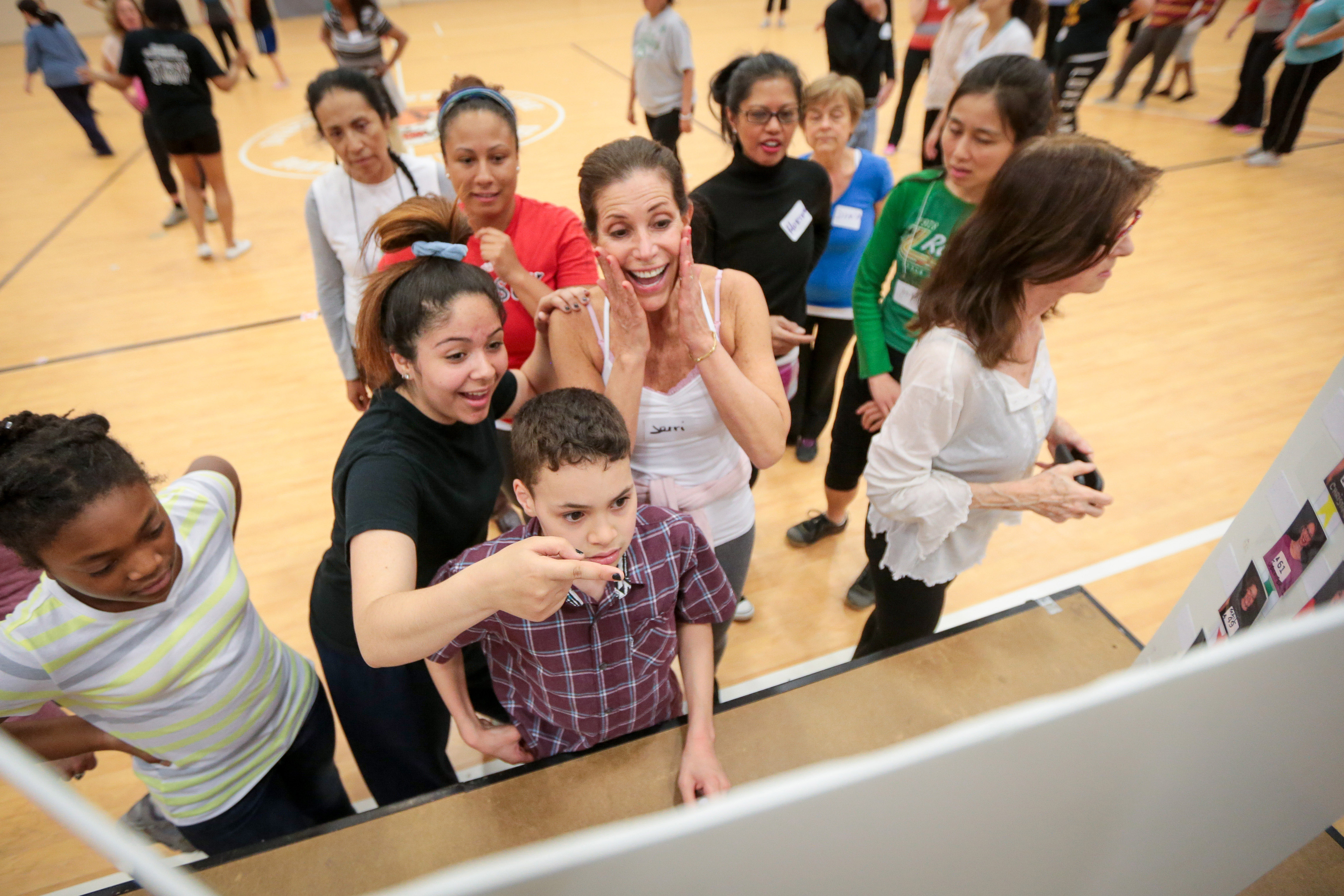 Dancers check the board for their photos and their positions for rehearsal.