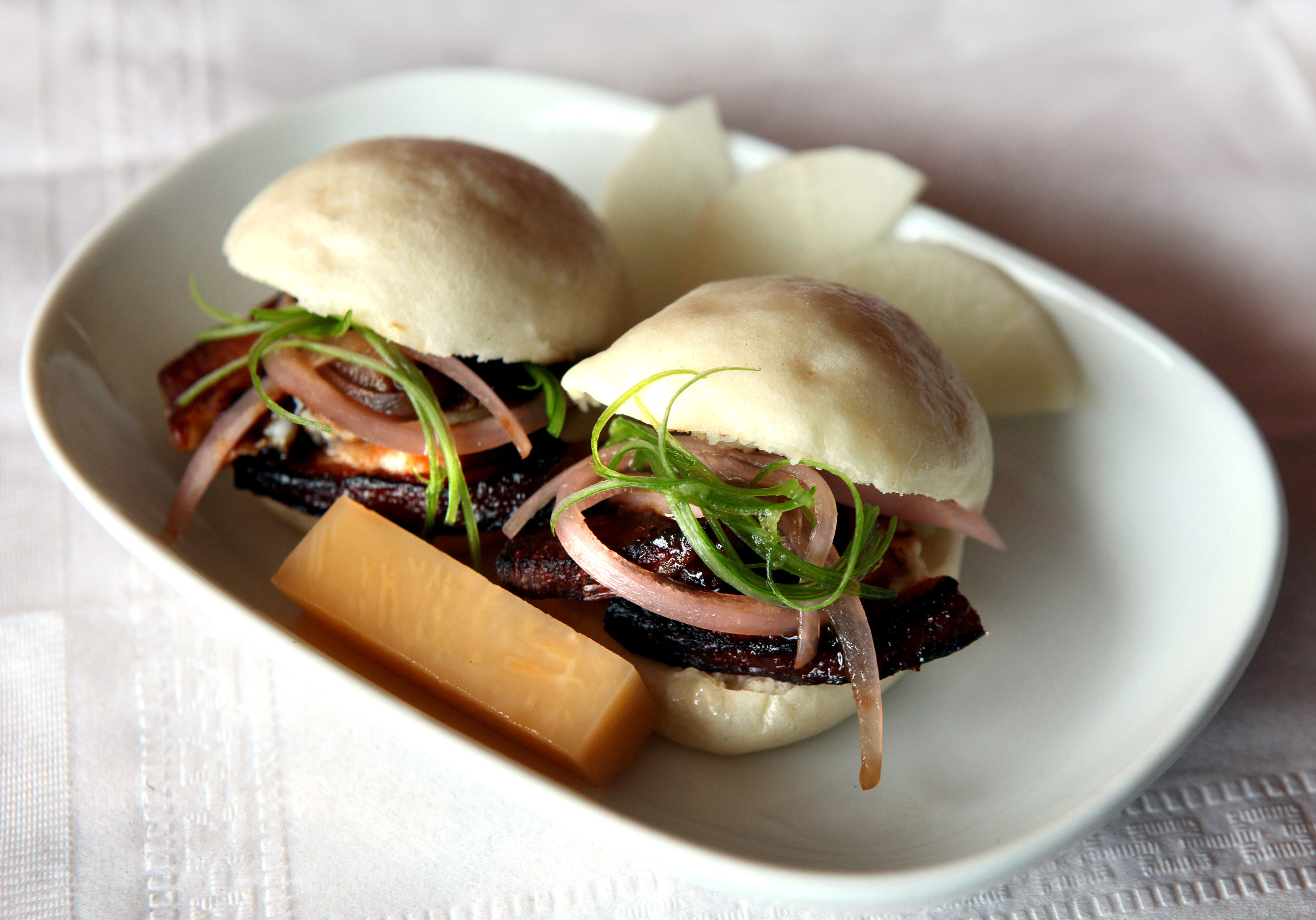 Dish of crispy pork belly, mantou bread, and pickled vegetables at East by Northeast.