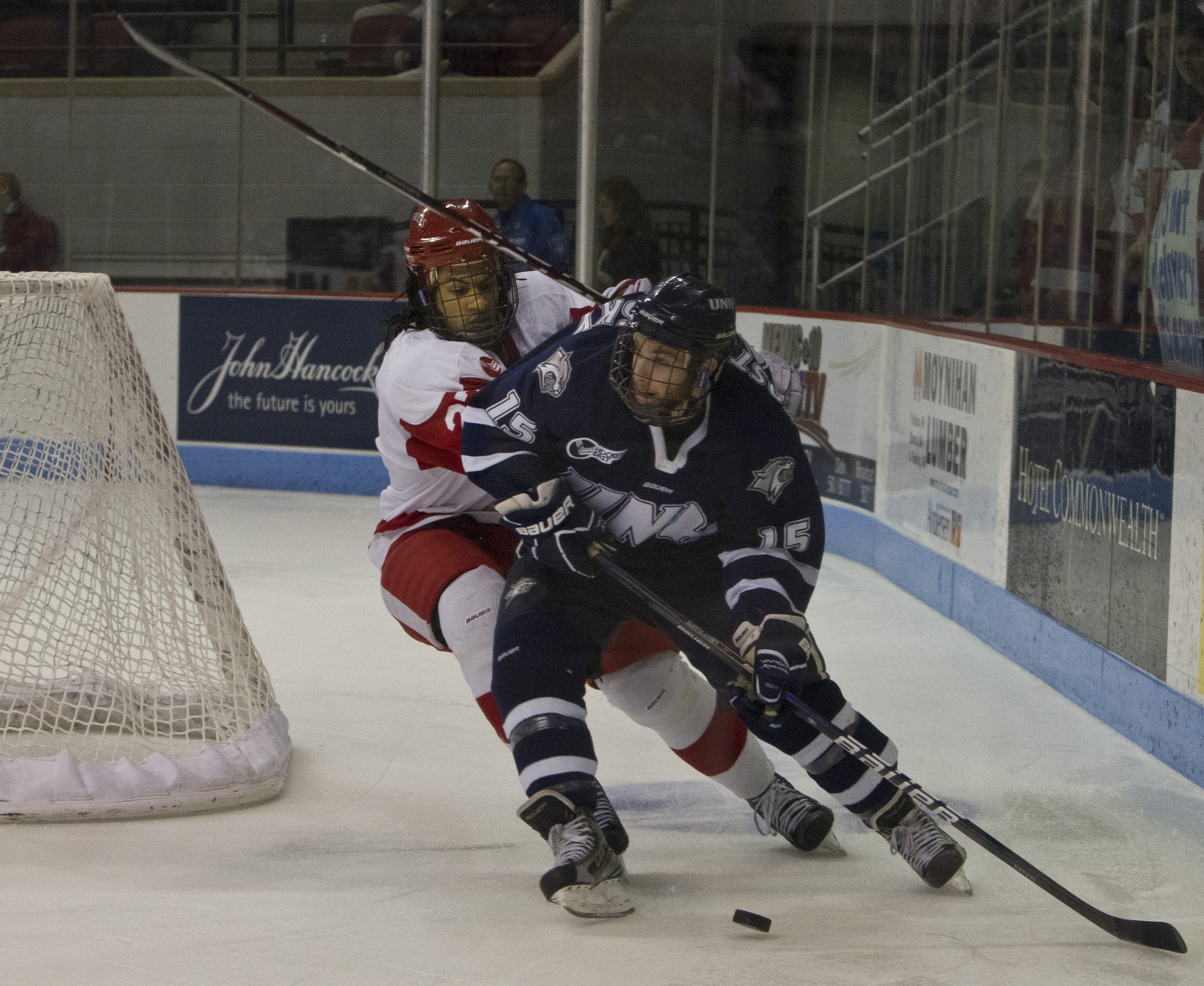 Yasin Cisse of BU attempts to separate the puck from UNH’s Brett Kostolansky during the third period at Agganis Arena.