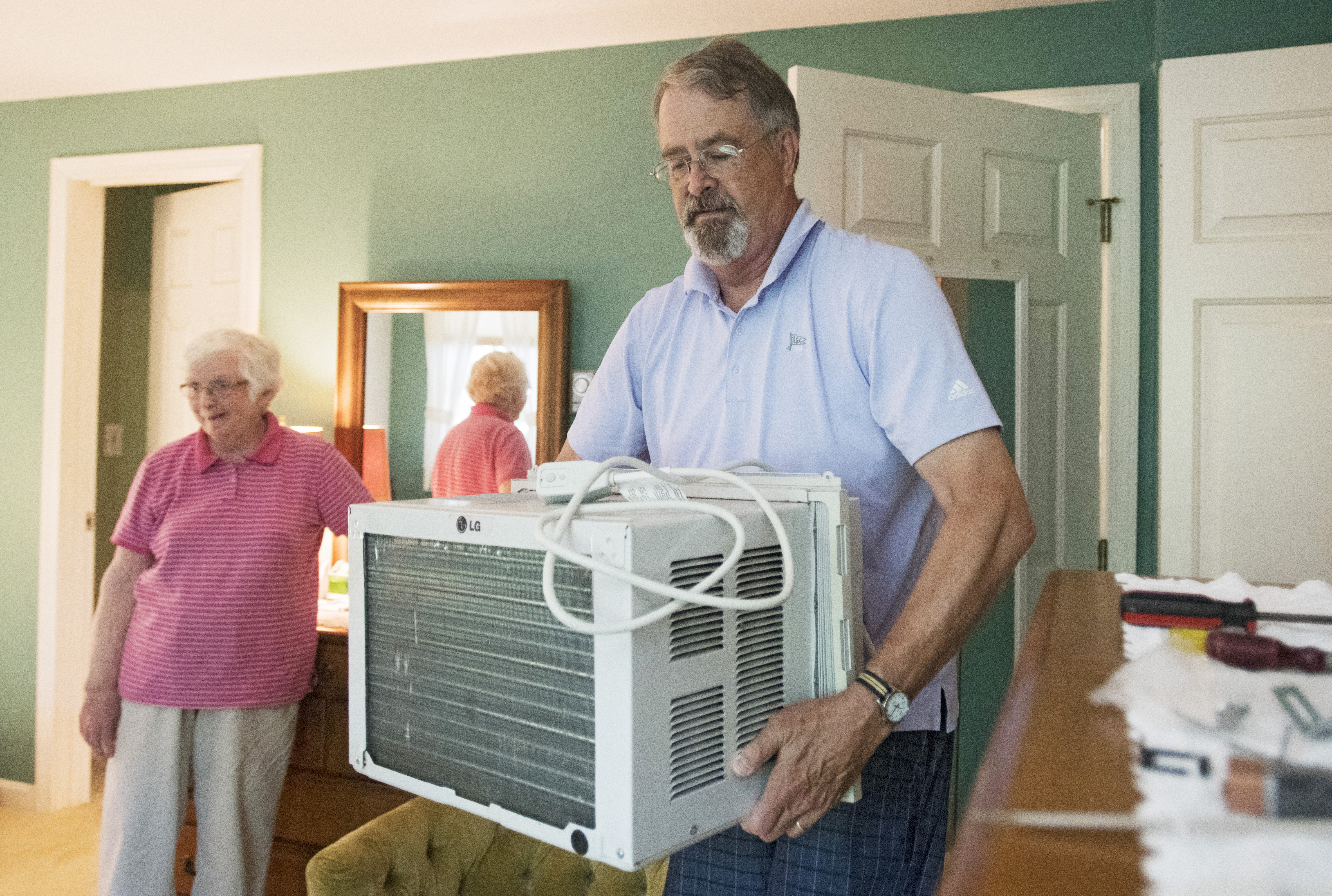 BREWSTER - Nauset Neighbors volunteer Frank Bridges, 66, installs an air conditioning unit for Ann Miller, 79, Tuesday, July 3, 2018.
