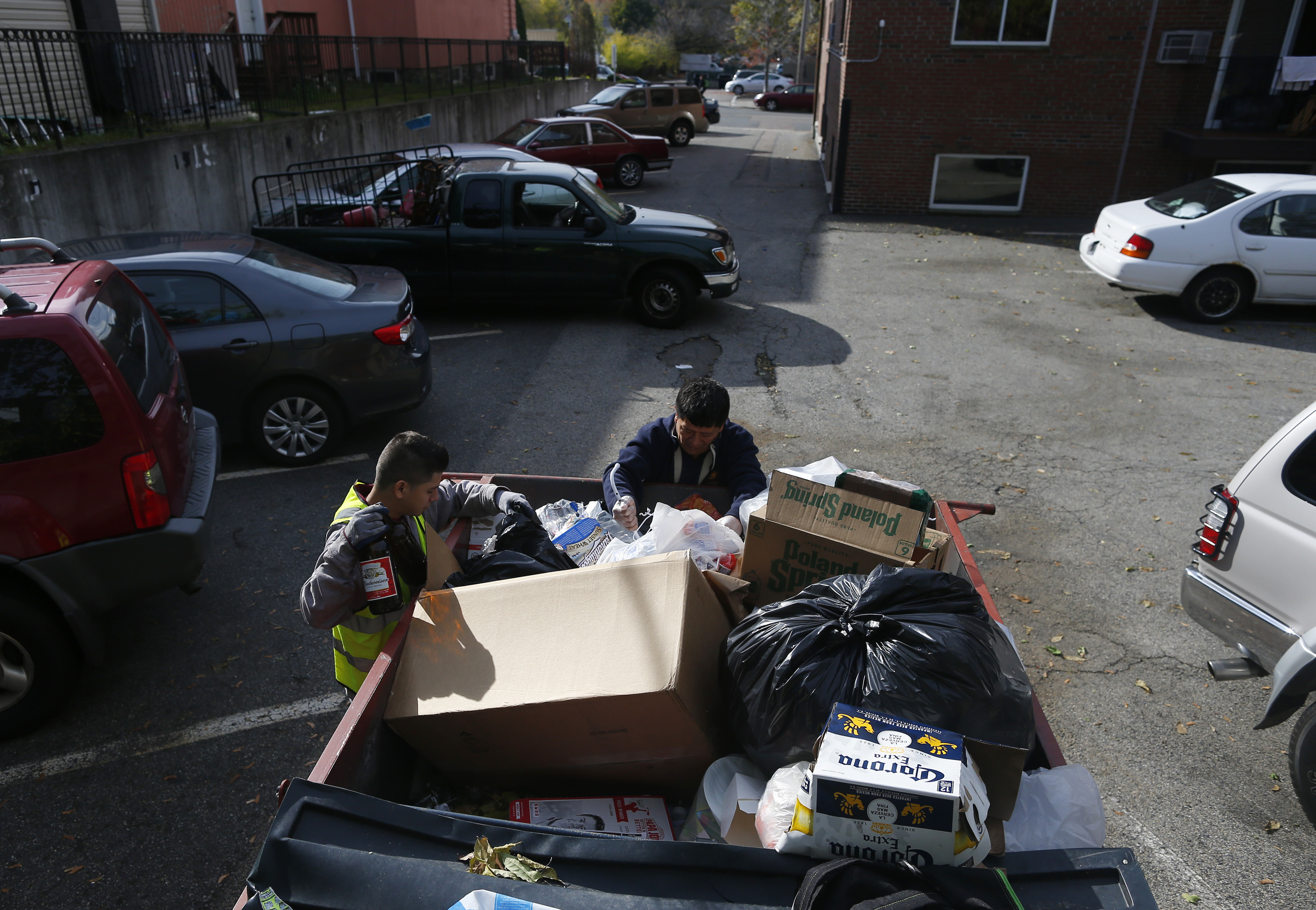 Jose Lopez, 23, (left) and his father, Reynabel Lopez, 46, of Allston looked through a dumpster in Brighton for cans and bottles to redeem for cash.