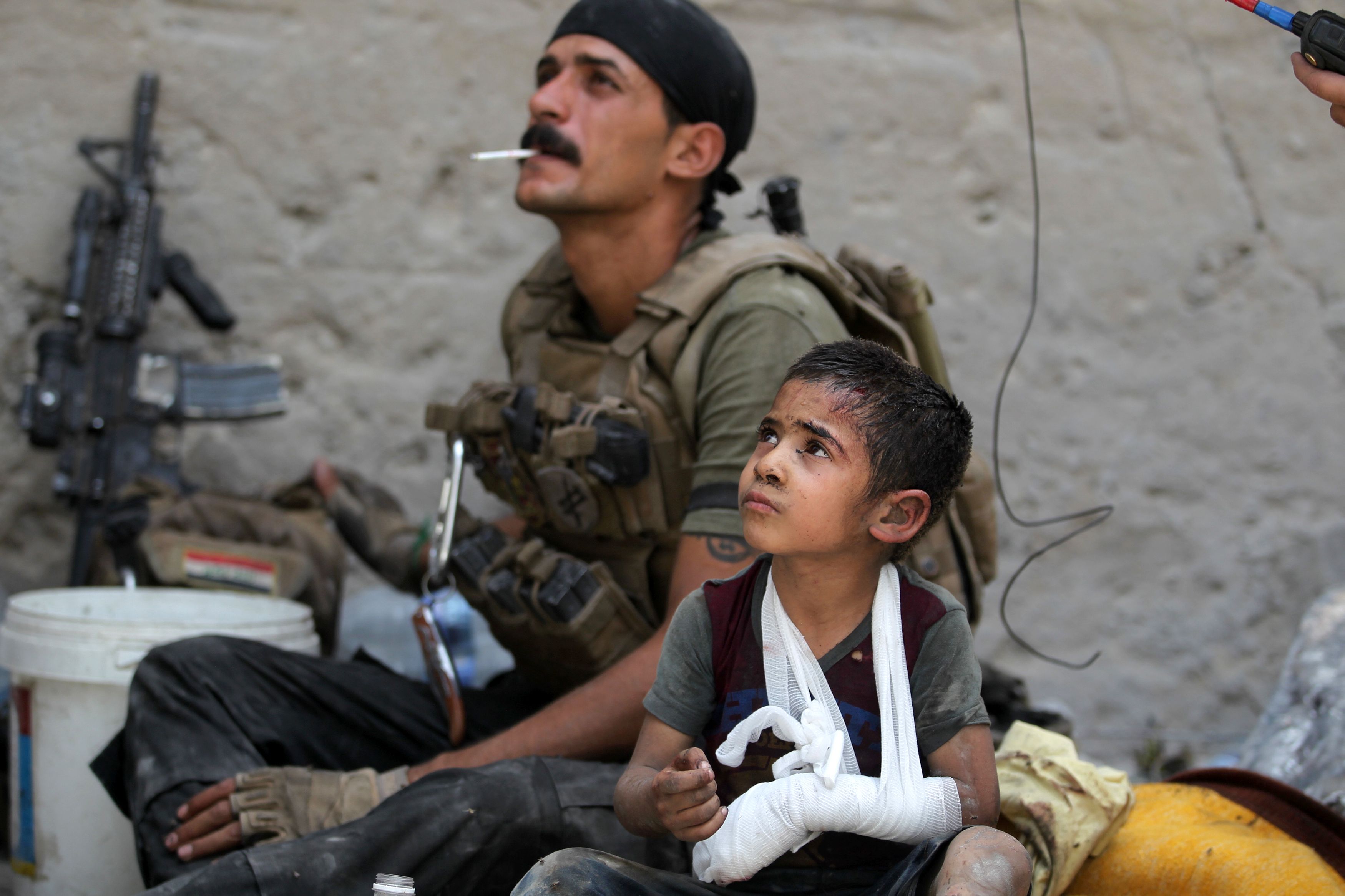 Omar, an Iraqi boy whose family was killed, sits with Counter-Terrorism Services members as they help him flee Mosul on July 3.