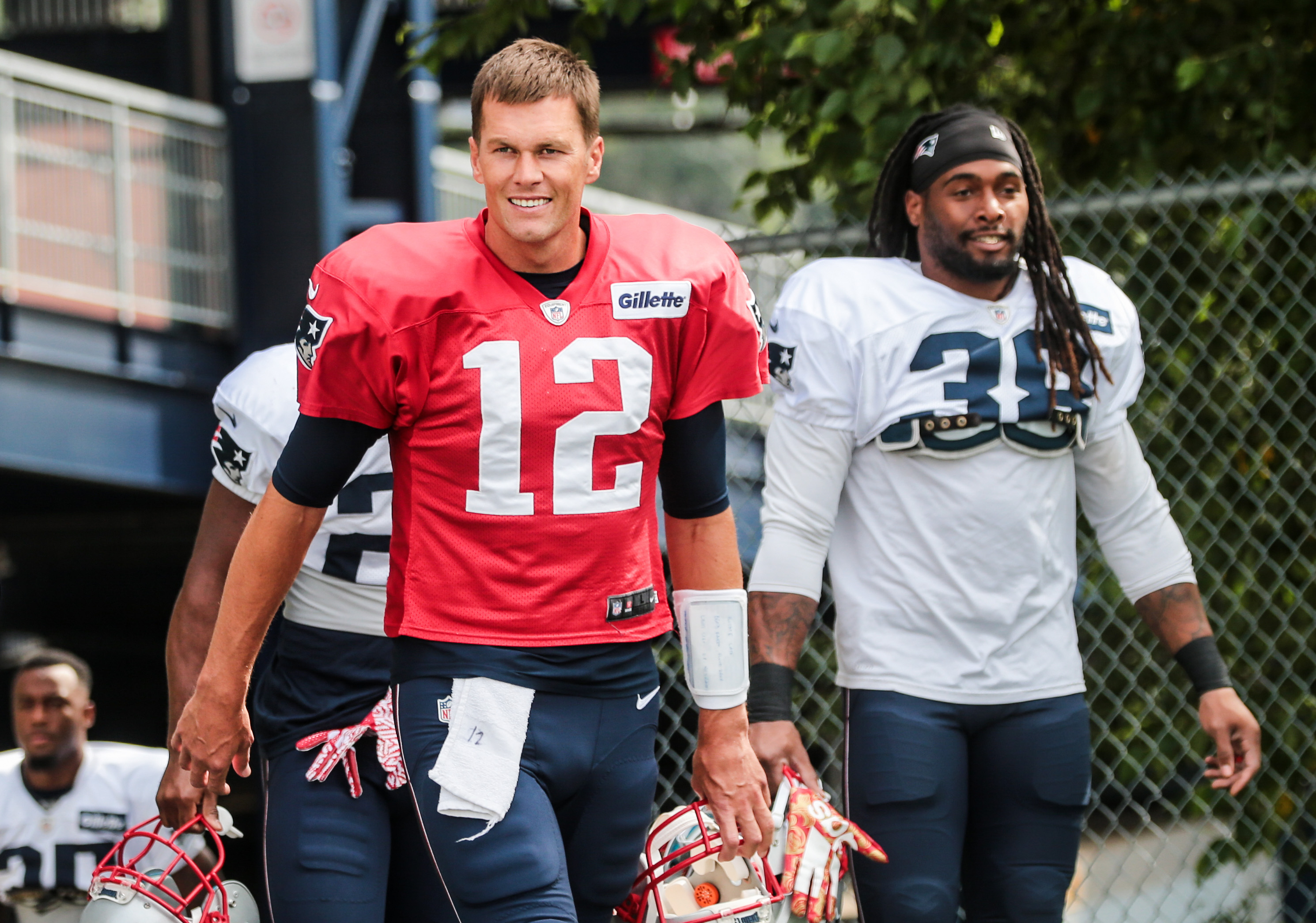Tom Brady (12) and Brandon Bolden walk onto the field for practice Monday.