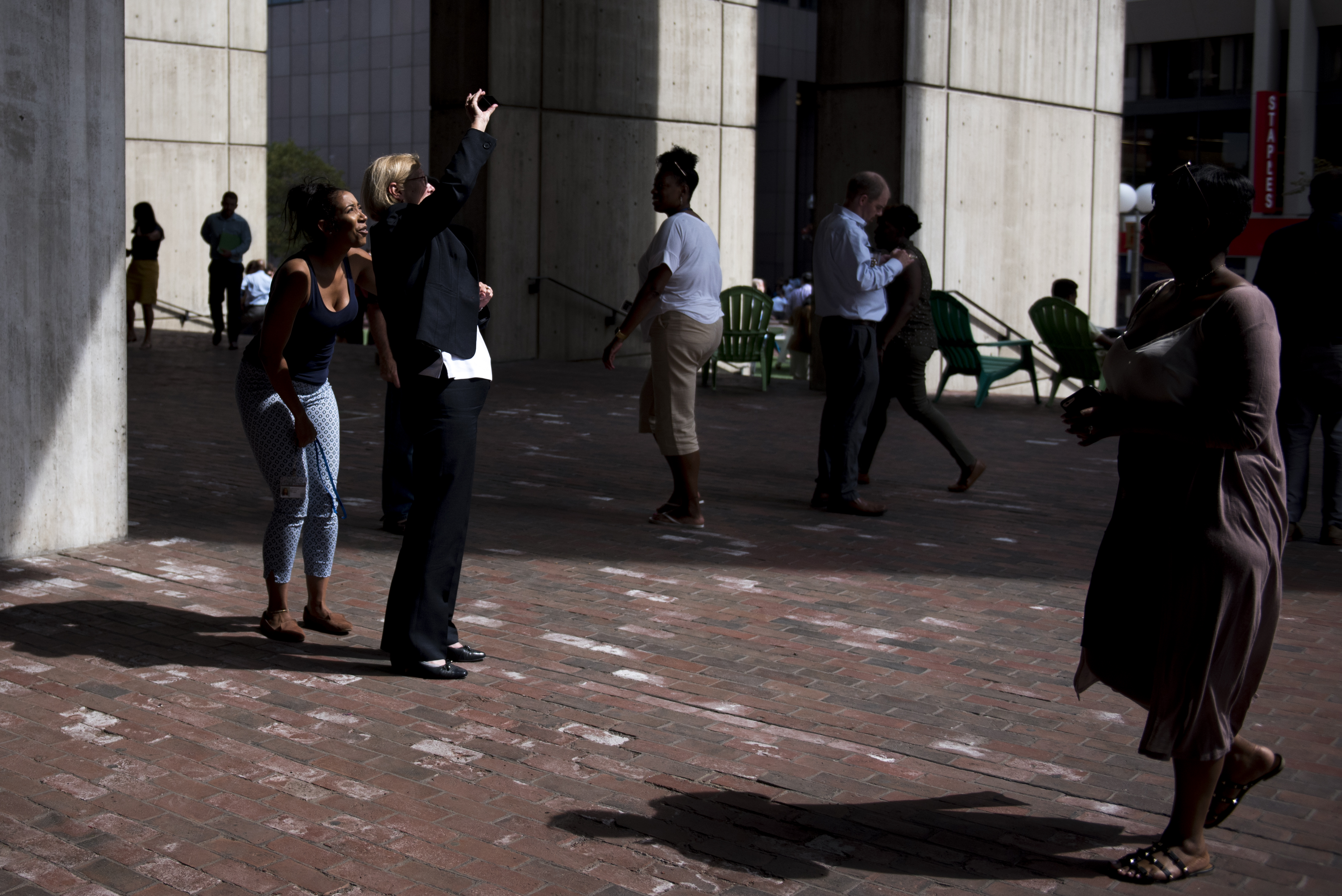 Sally Glora, center, and Teki,, left, check out the sun during the partial solar eclipse in City Hall Plaza.