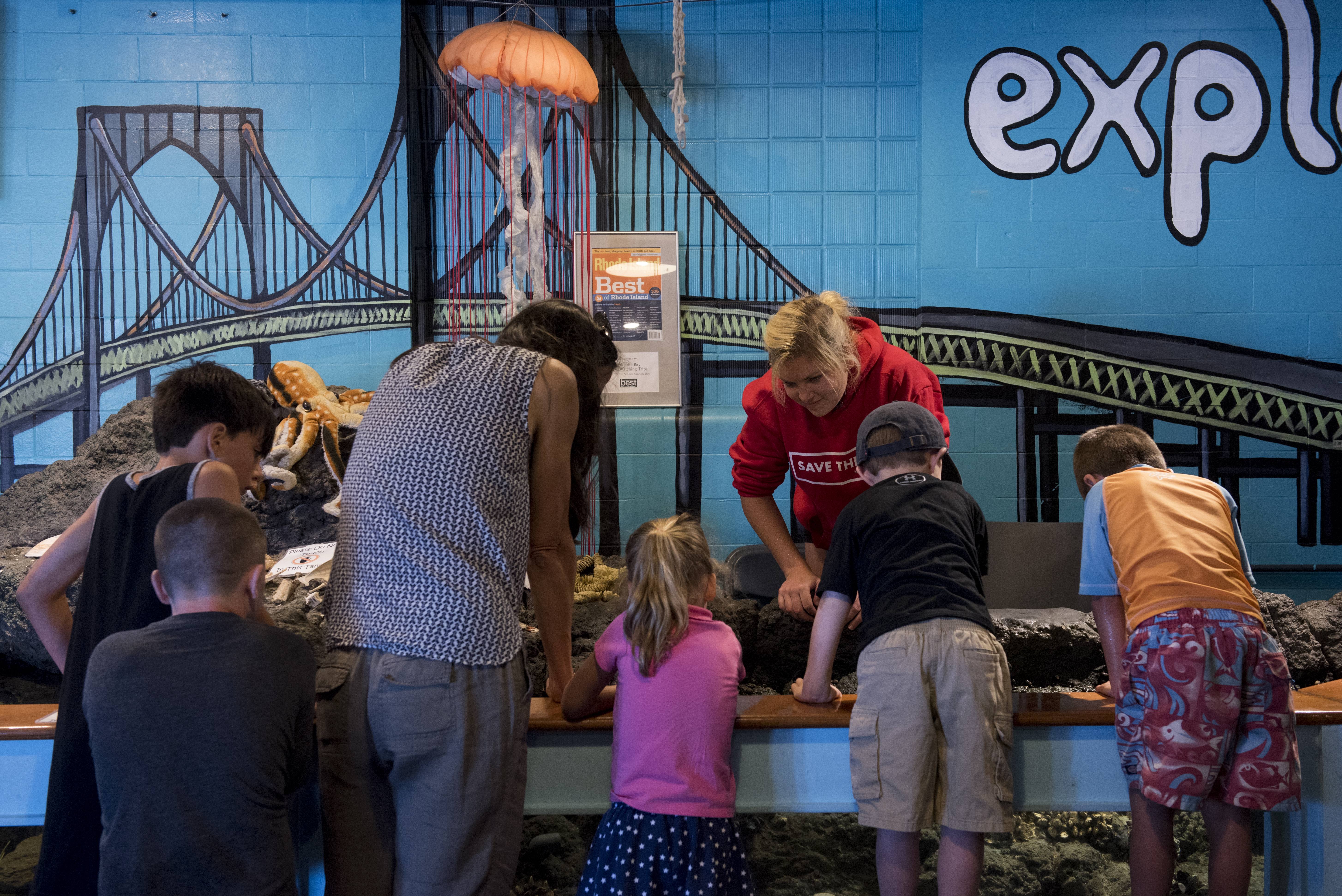 Kate Hoey, a summer intern at Save the Bay Exploration Center & Aquarium, shows children crabs and starfish.