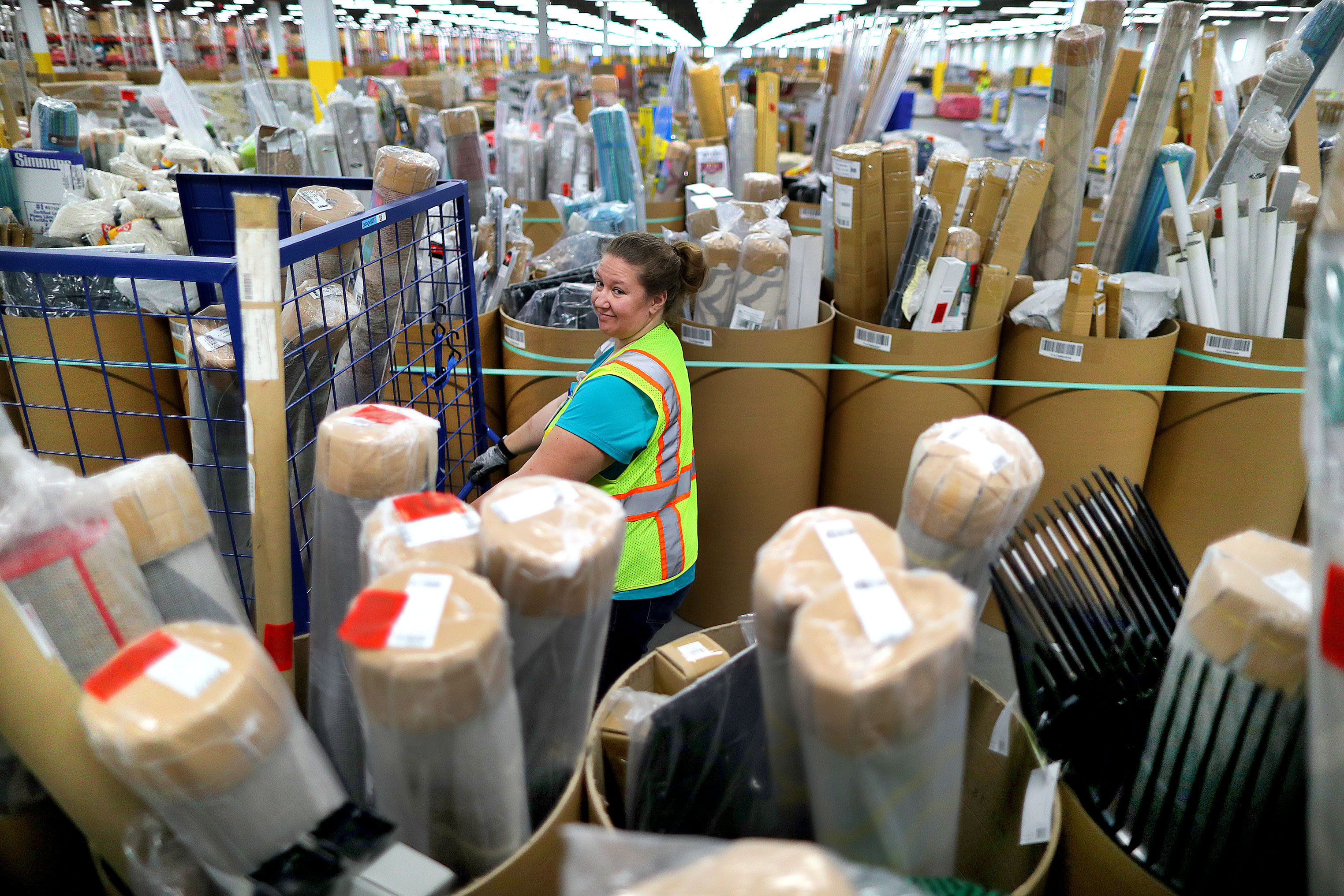 Worker Kathleen Frey loads a cart with customer orders from rows and rows of items stored in tubes.