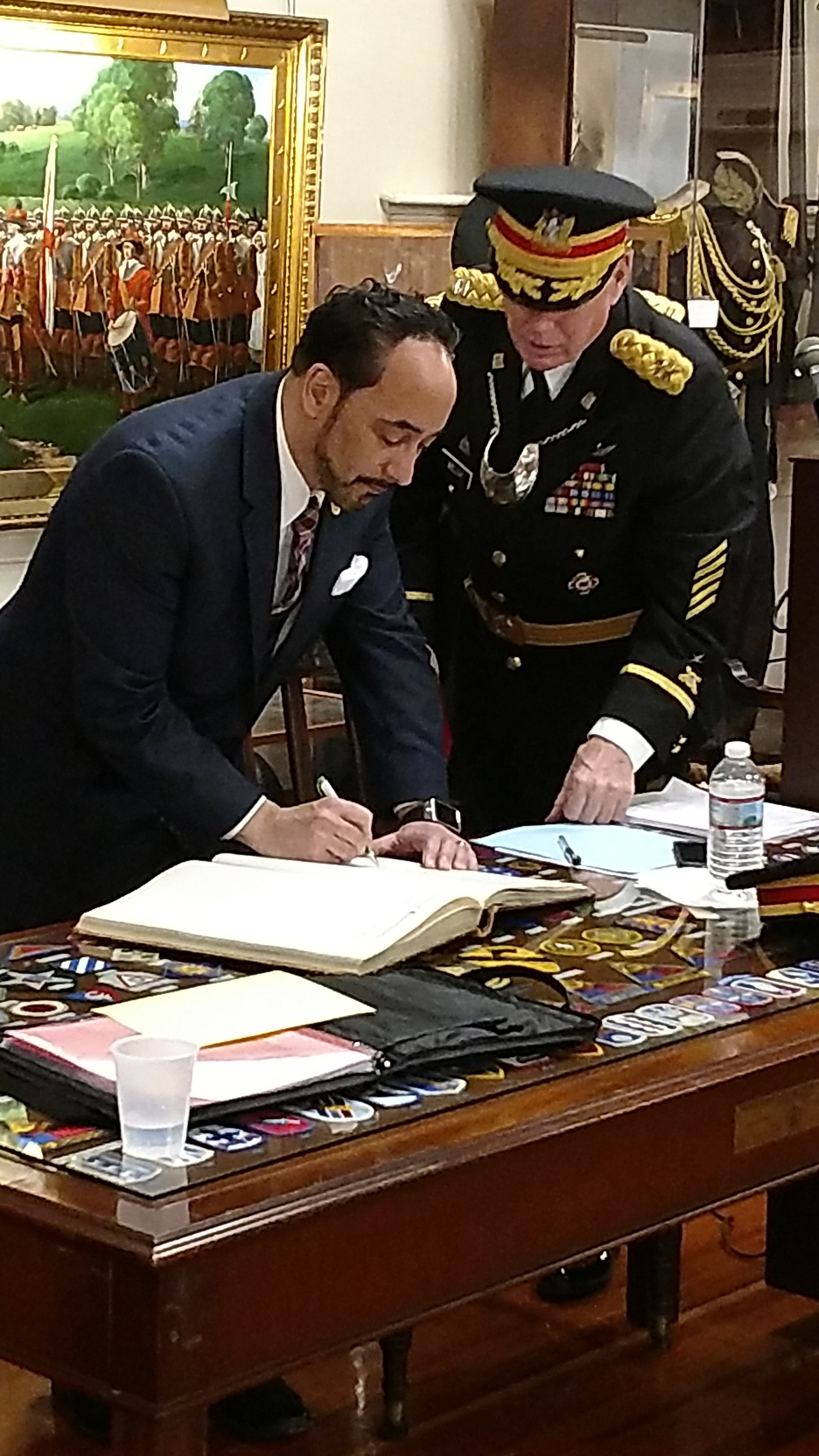 Retired US Air Force Lt. Col. Vincent J. Perrone signs the historic membership book of the Ancient and Honorable Artillery Company of Massachusetts while Captain Commanding Brigadier General Robert E. Welch looks on.