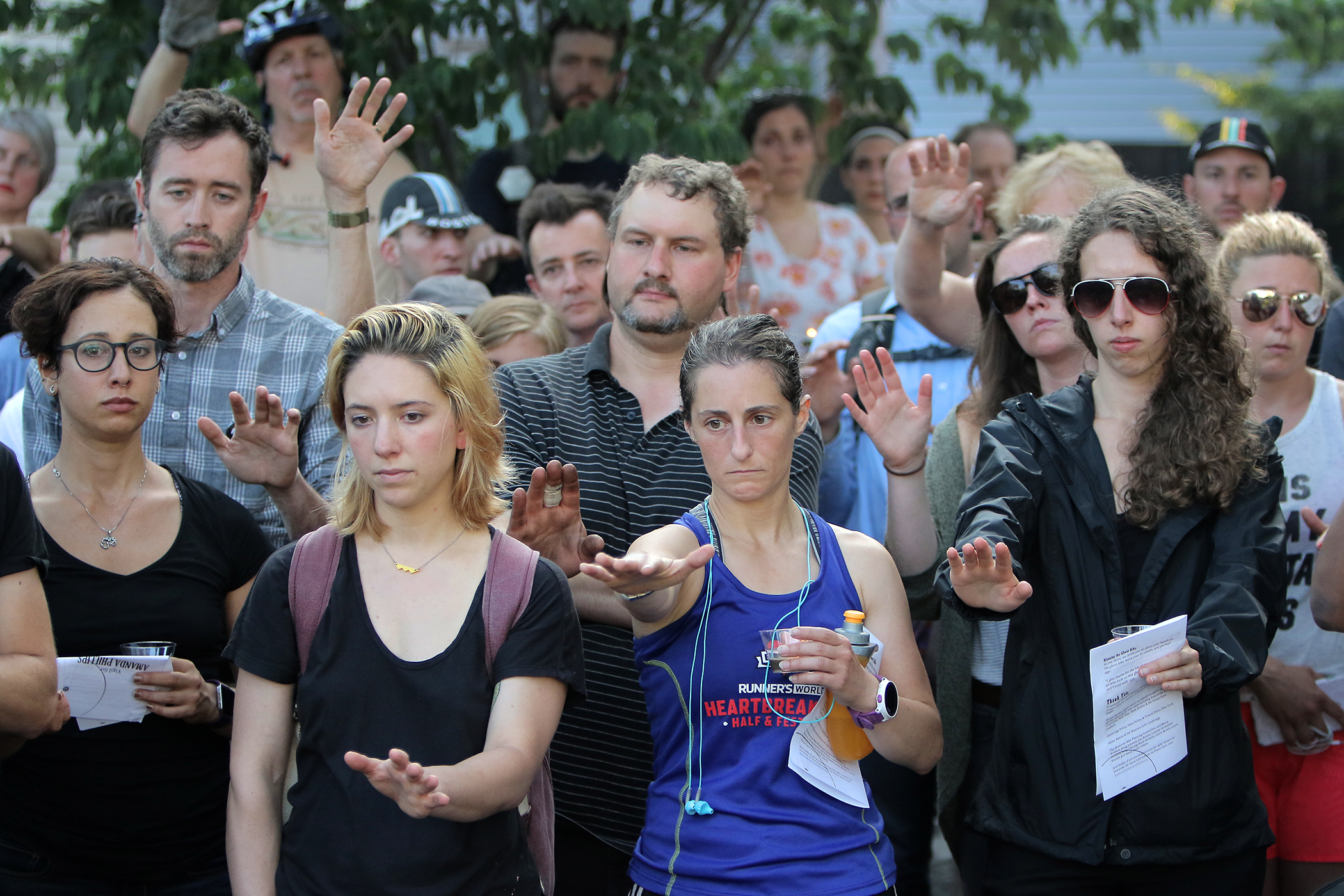 Mourners reach out to touch a ghost bike at a vigil for Amanda Phillips, who was killed while riding a bike in Inman Square.