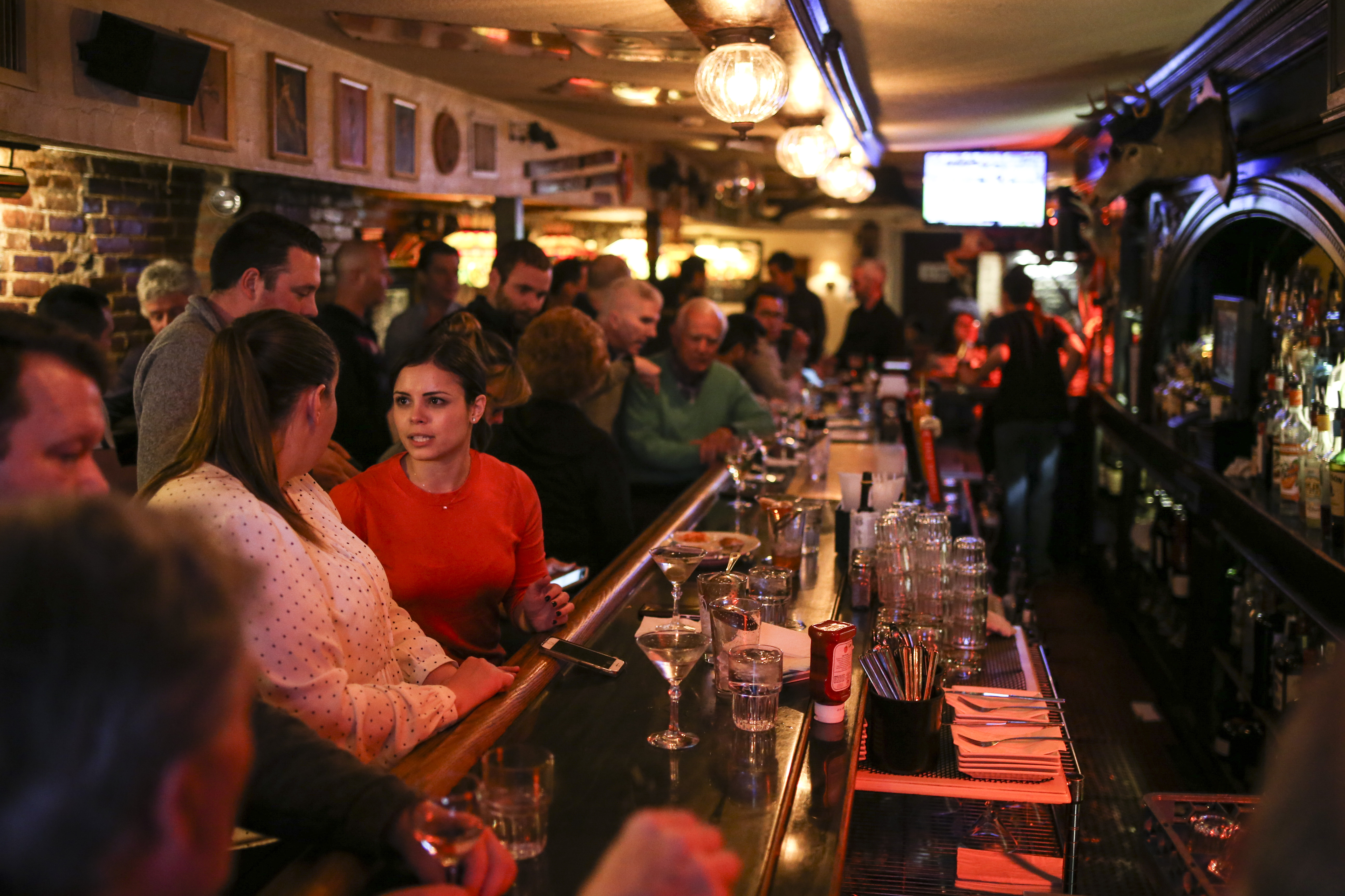 A crush of people at the ornately carved mahogany bar.