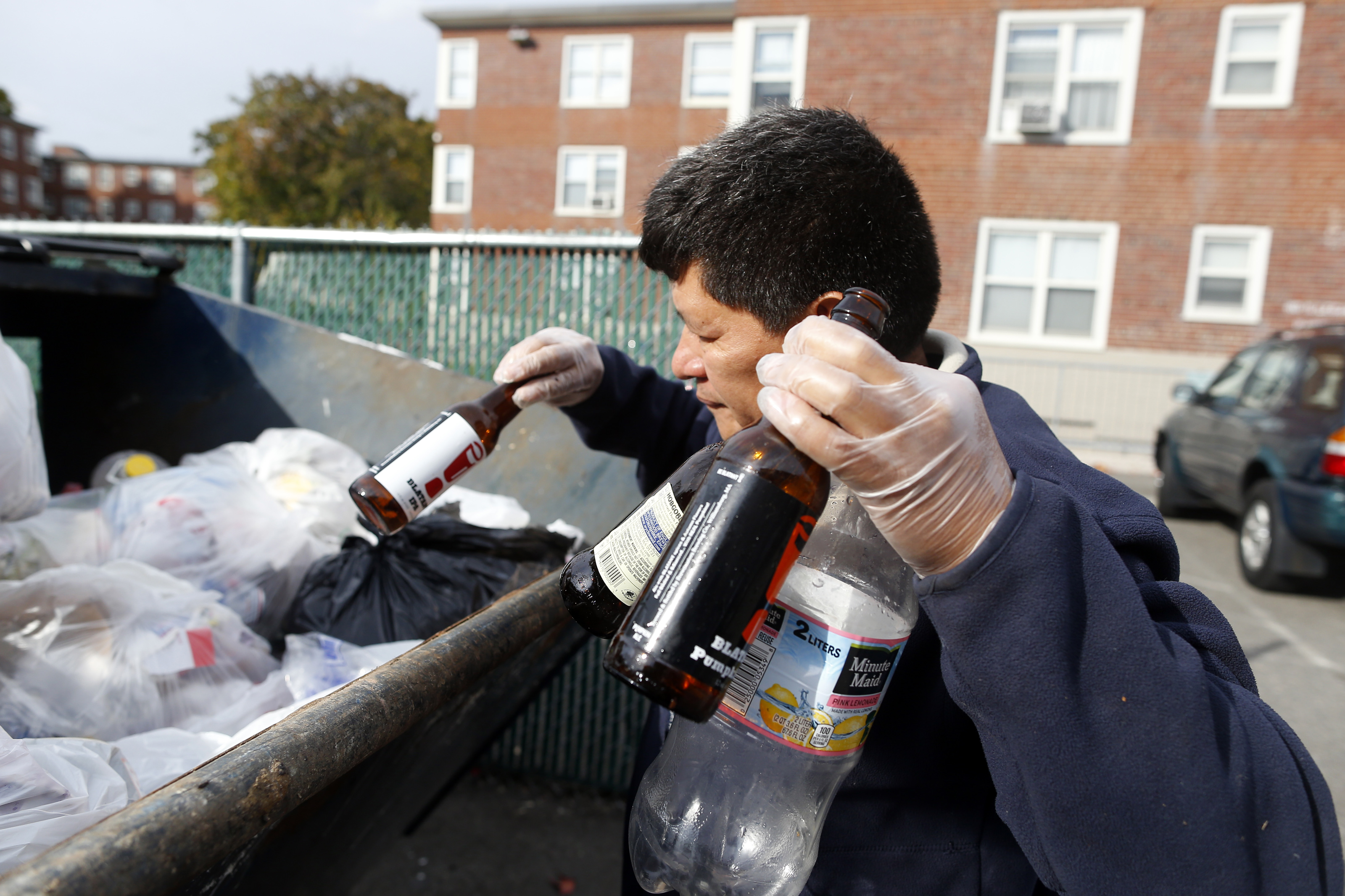 Reynabel Lopez, collecting bottles from a dumpster in Brighton, regularly patrols the city for recyclable cans and bottles. An expanded deposit law would benefit those who collect.