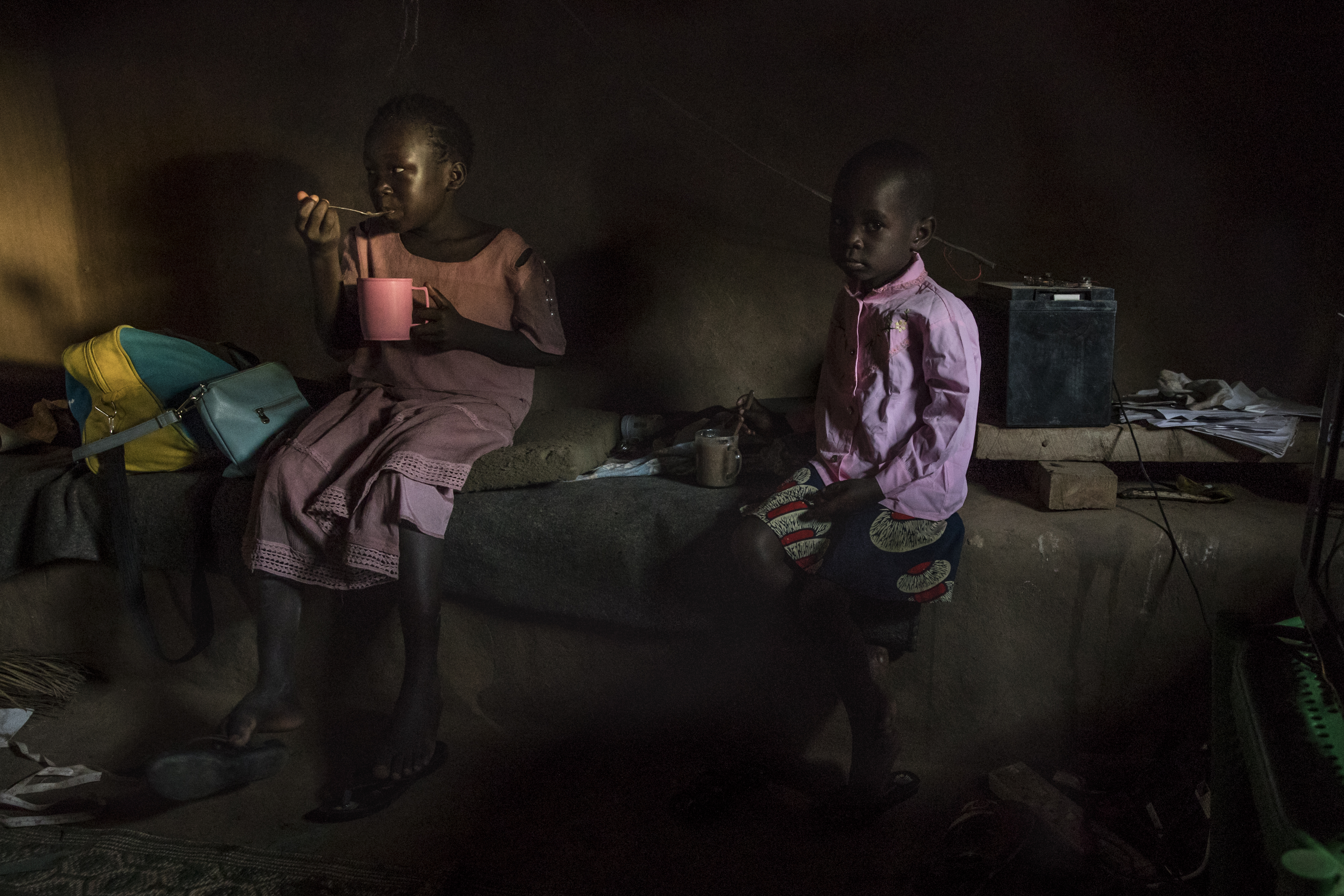 Lynda (left) and Julie (right), daughters of Achayo Loum, sat in the family’s home in the UNHCR refugee camp.