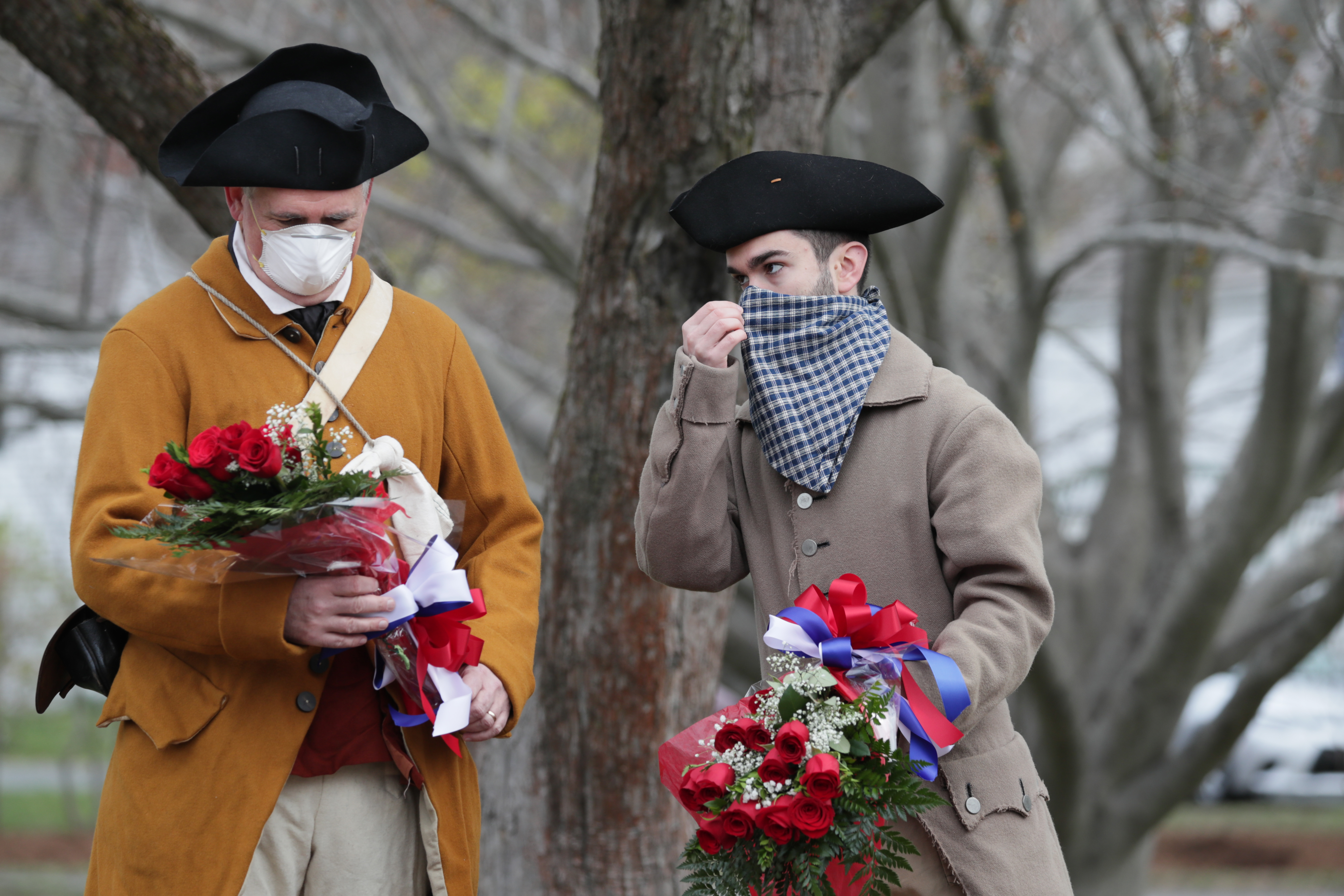 Minutemen reenactors John Kiernan and Sam Doran laid flowers on a monument next to the Buckman Tavern Monday morning in Lexington.