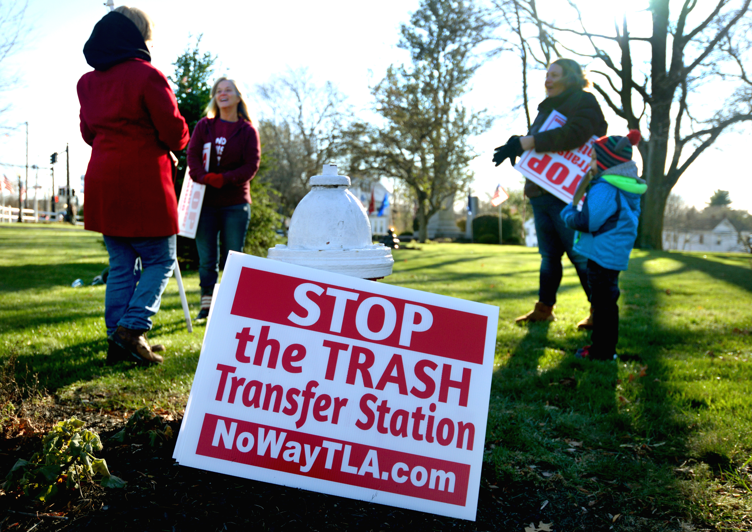 (From left) Patricia Greeley, Annie Barker, and Janelle Farrar with her 5-year-old son, Gustin, prepared to protest in Holbrook Square against the trash transfer station approved by the Holbrook Board of Health.