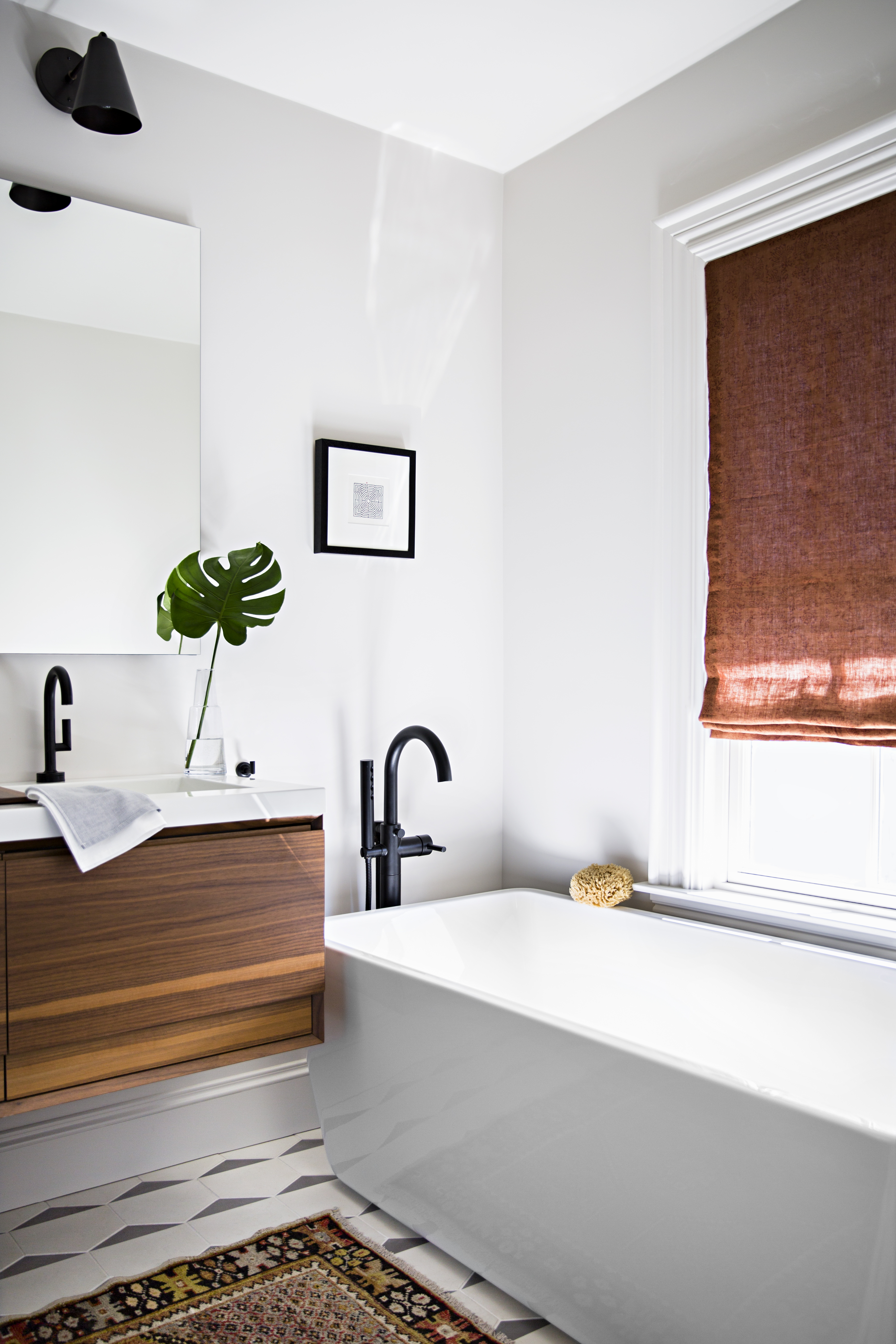 In the new master bath, the American Standard Sedona Loft soaking tub sits in the same spot as the old tub. The freestanding tub-filler fixture is by Jason Wu for Brizo, and the Cle Tile flooring has radiant heat. The subtle hand-blocked Roman shade fabric is Alamwar Textiles Anjali Creeper from Studio Four NYC.