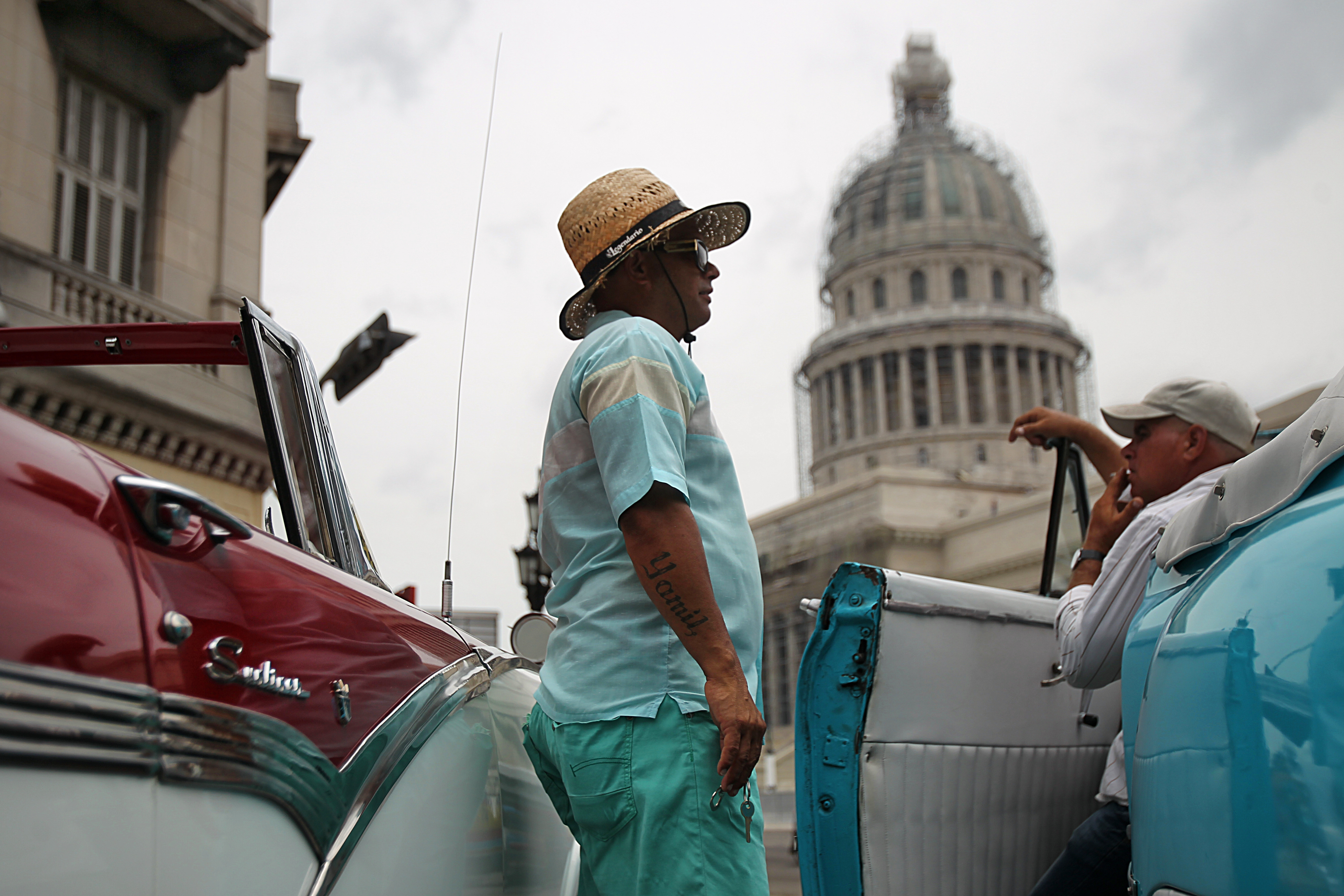 Taxi drivers with their restored antique cars wait for tourists in front of the Capitol.