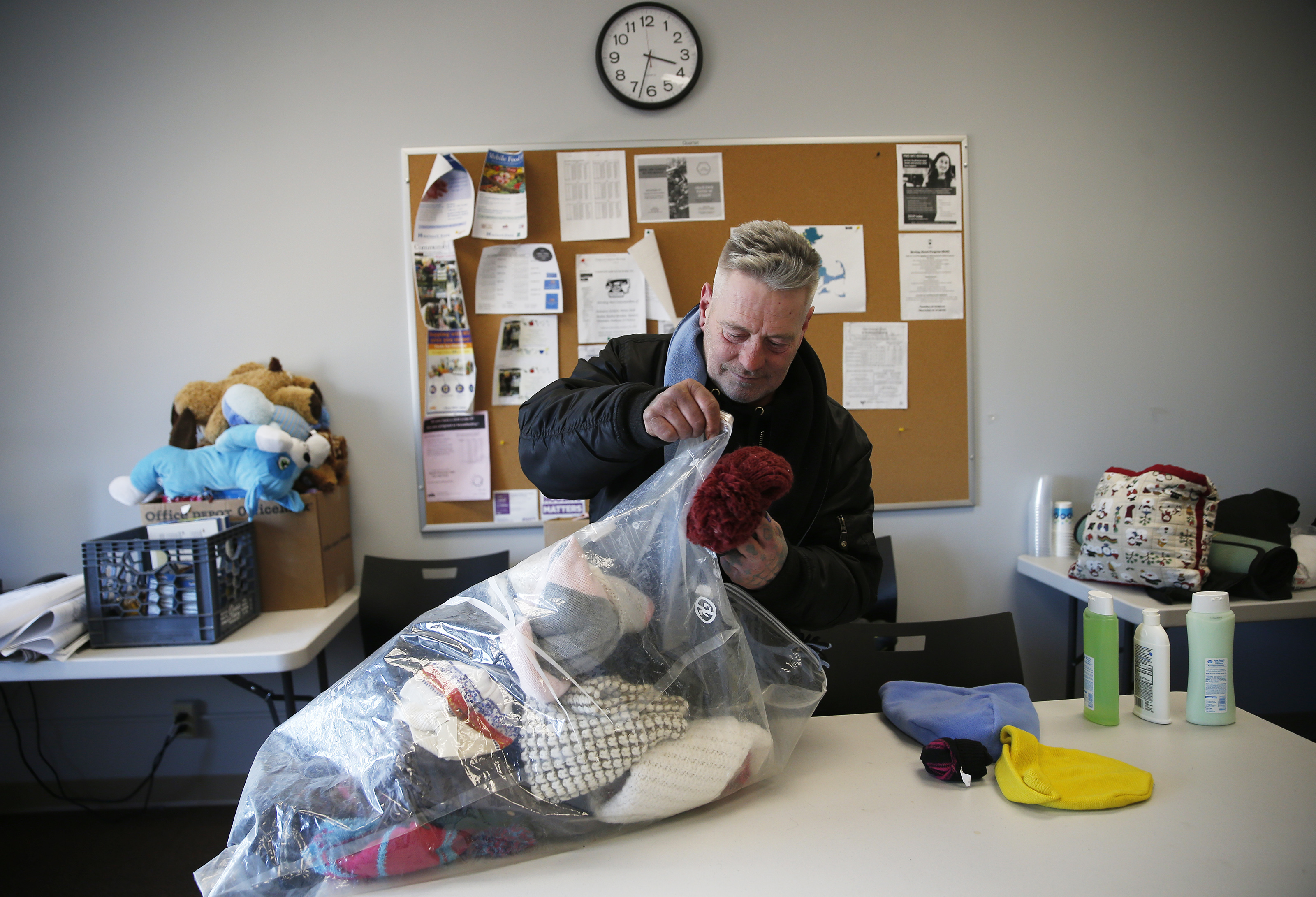 After getting picked up by the Mobile Homeless Outreach Team, James searches through a bag of donated hats inside the ABCD office in Malden.