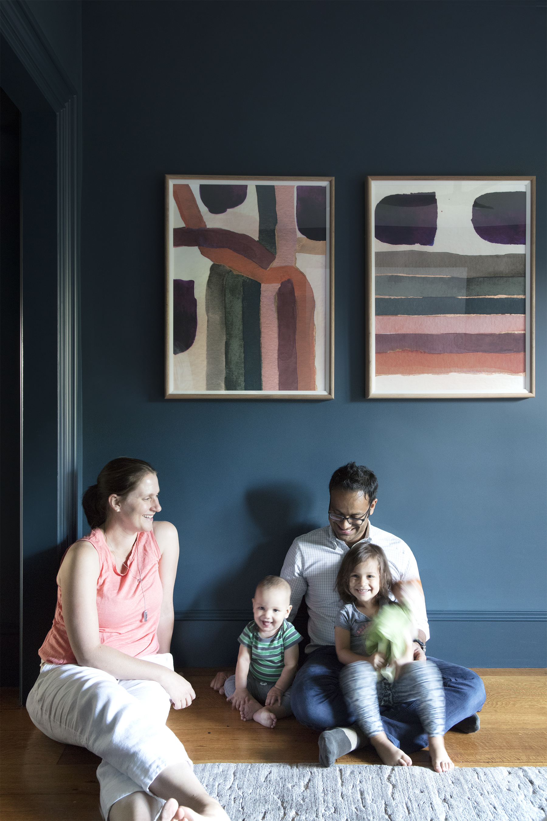 Melissa Spencer, Raj Basu, and their children relax in the master bedroom, where limited-edition abstract prints from Zoe Bios Creative add a pop of color.