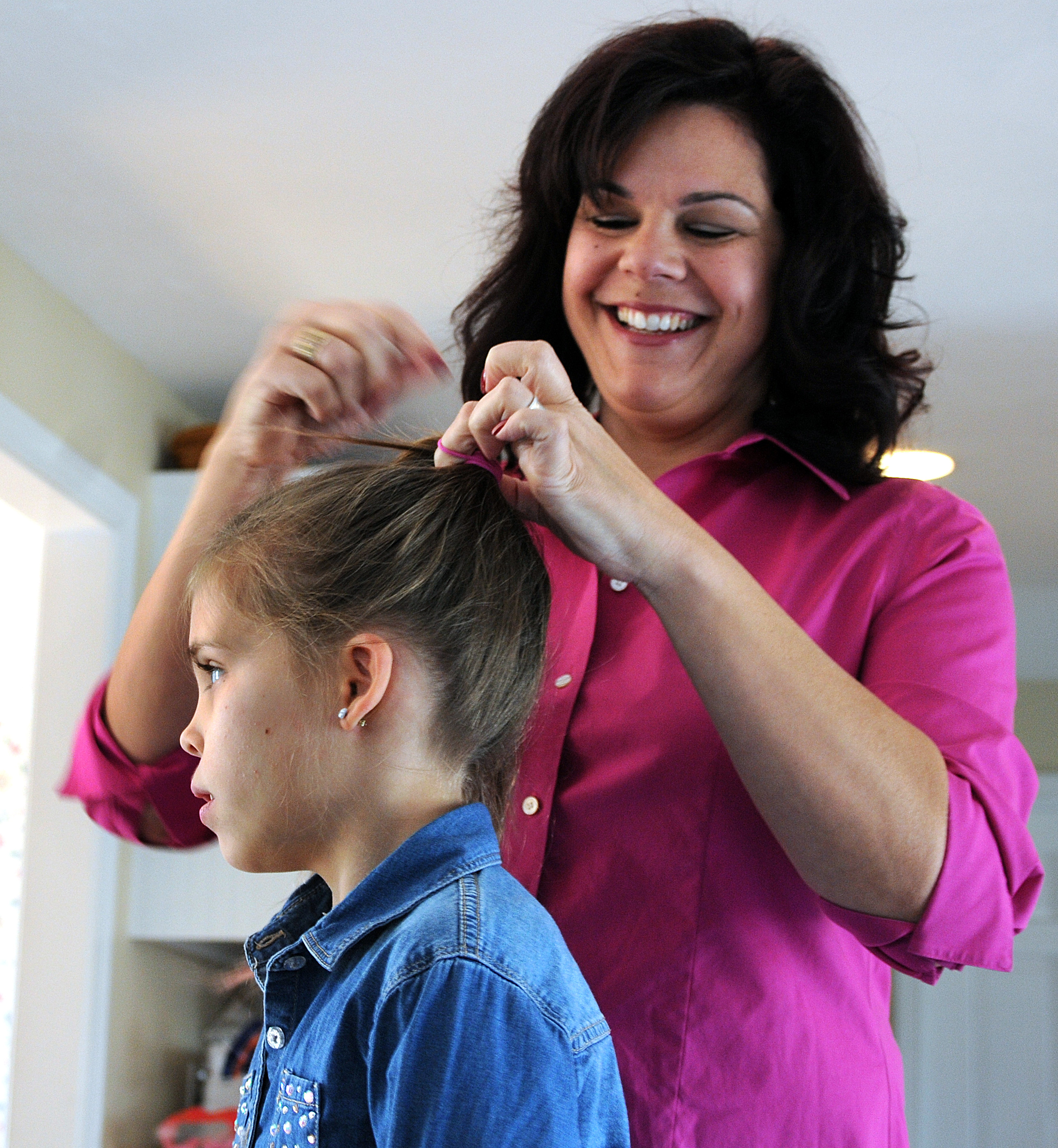 Melanie Feehan of Plymouth works on her daughter Leela’s hair.