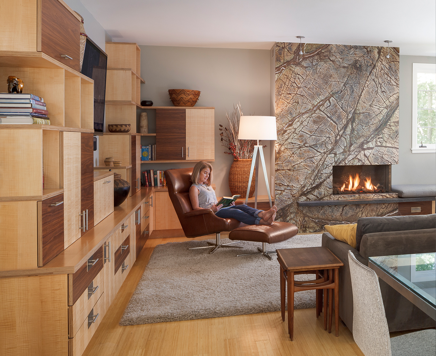 In the family room, homeowner Catherine Riedel relaxes in a leather Beau chair from Room & Board. Architect Gary Wolf designed the custom cabinetry; the exposed edges contribute to the modern feel. Each child has a cabinet to store schoolbooks; a charging drawer corrals electronic devices.