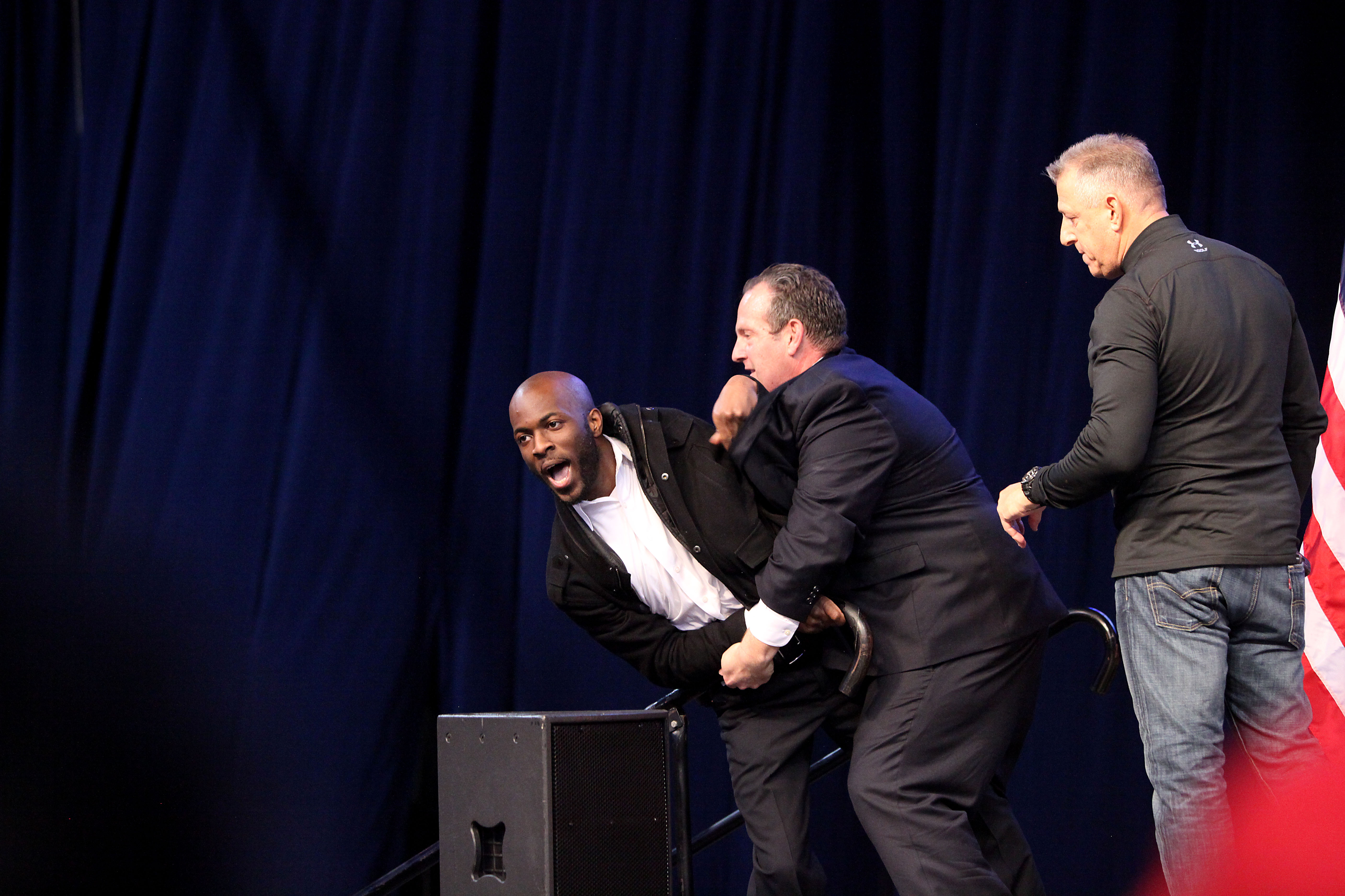 A protester is wrestled off the stage after a campaign rally for Donald Trump was canceled, at the UIC Pavilion in Chicago.