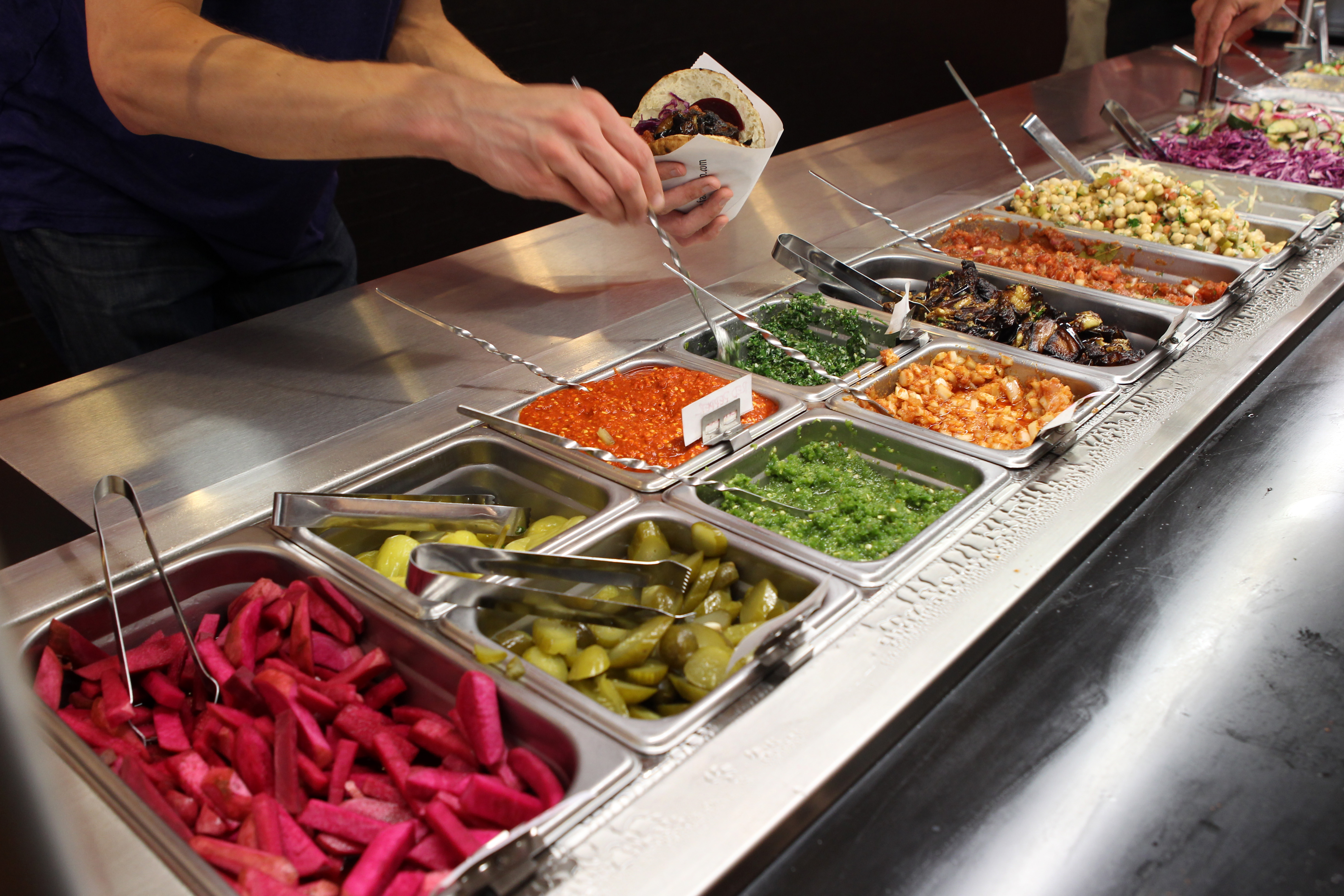 Many toppings to add to falafel sandwiches or bowls at Amsterdam Falafel Shop in Davis Square.