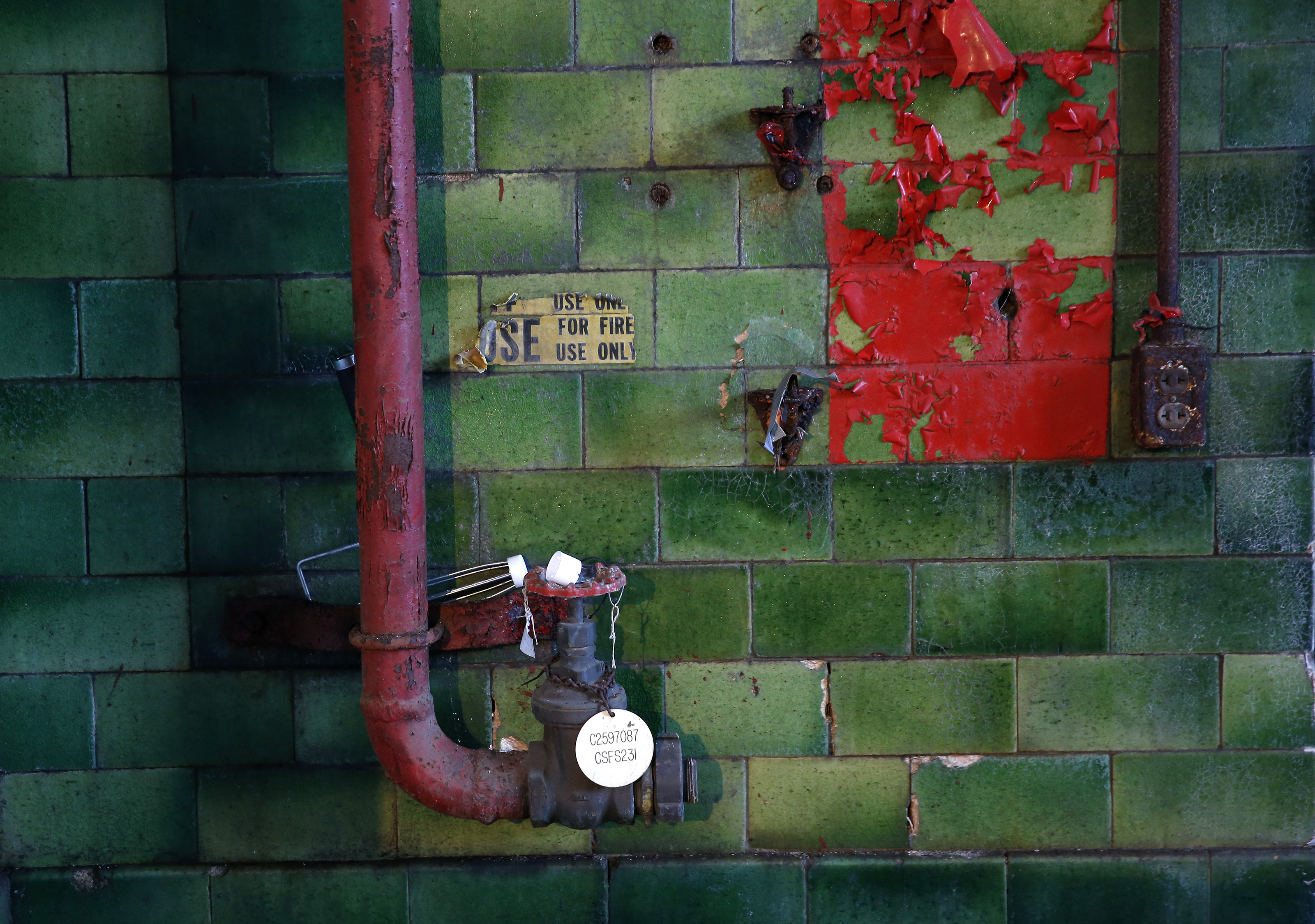 A square of red paint is peeling from the green subway tiles inside the L Street Power Station.