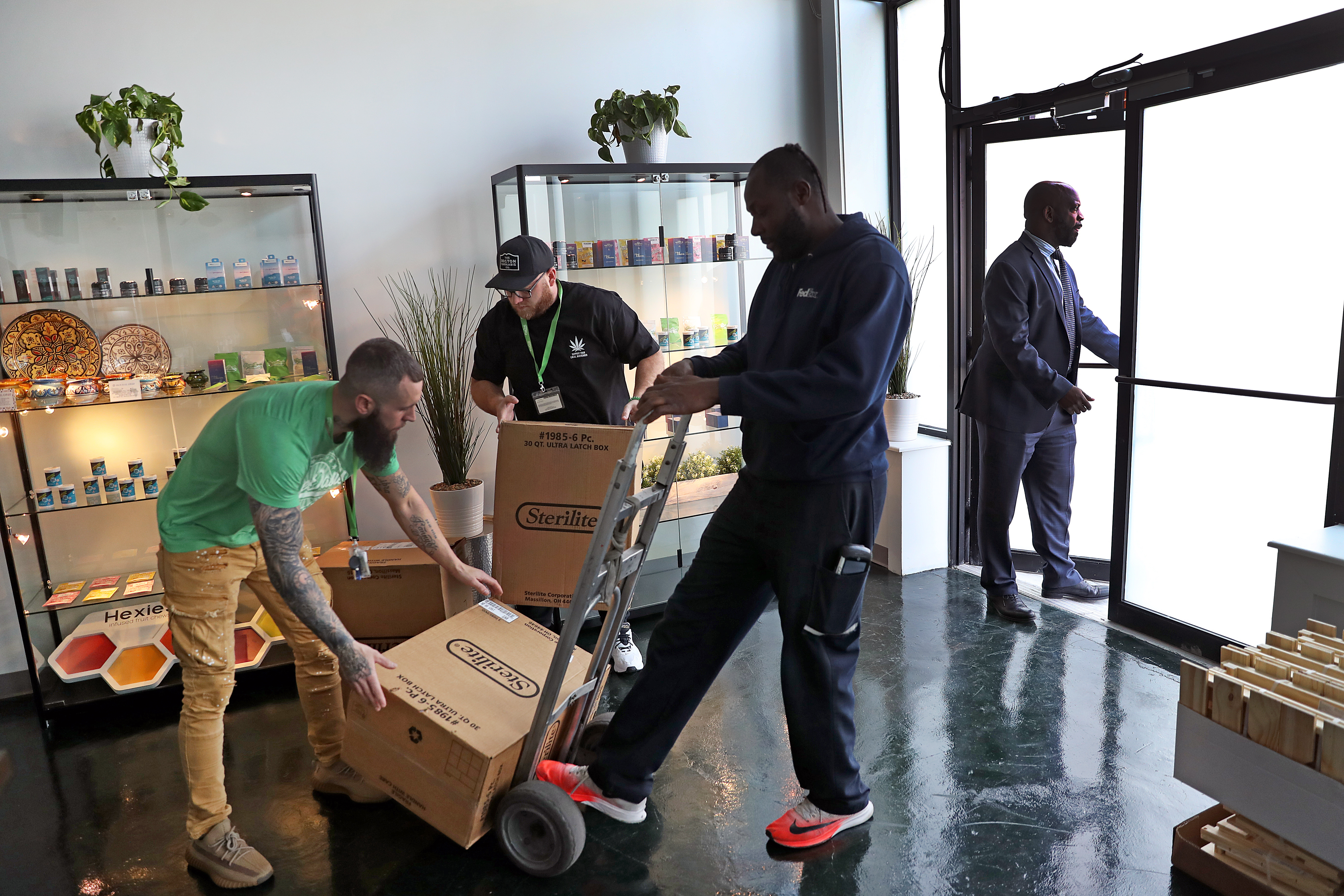 Pure Oasis employees move shipment boxes to prepare for the store's opening day Monday.