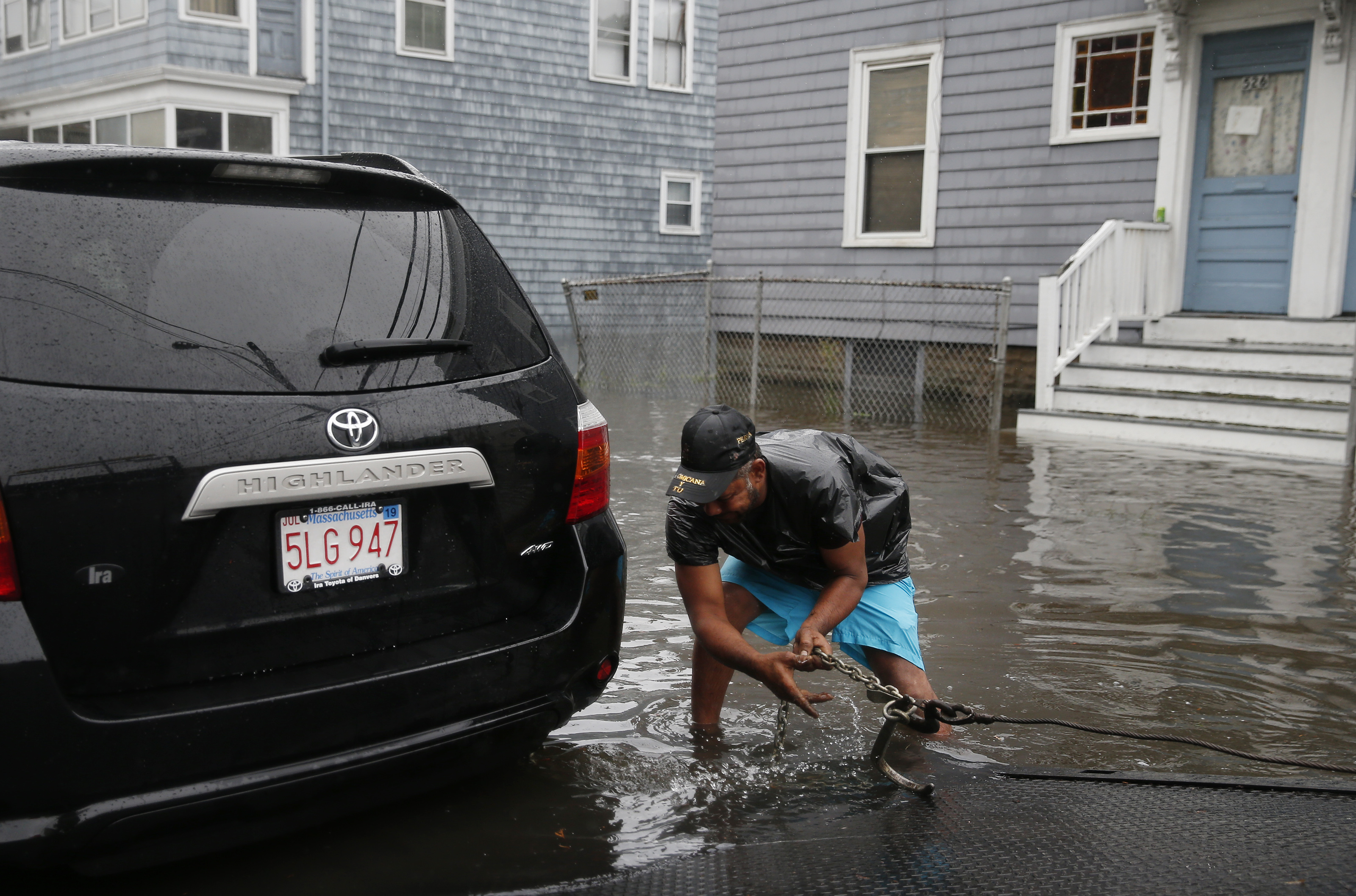 A tow truck driver worked to pull a stranded car out of the flood waters on Boston Street.