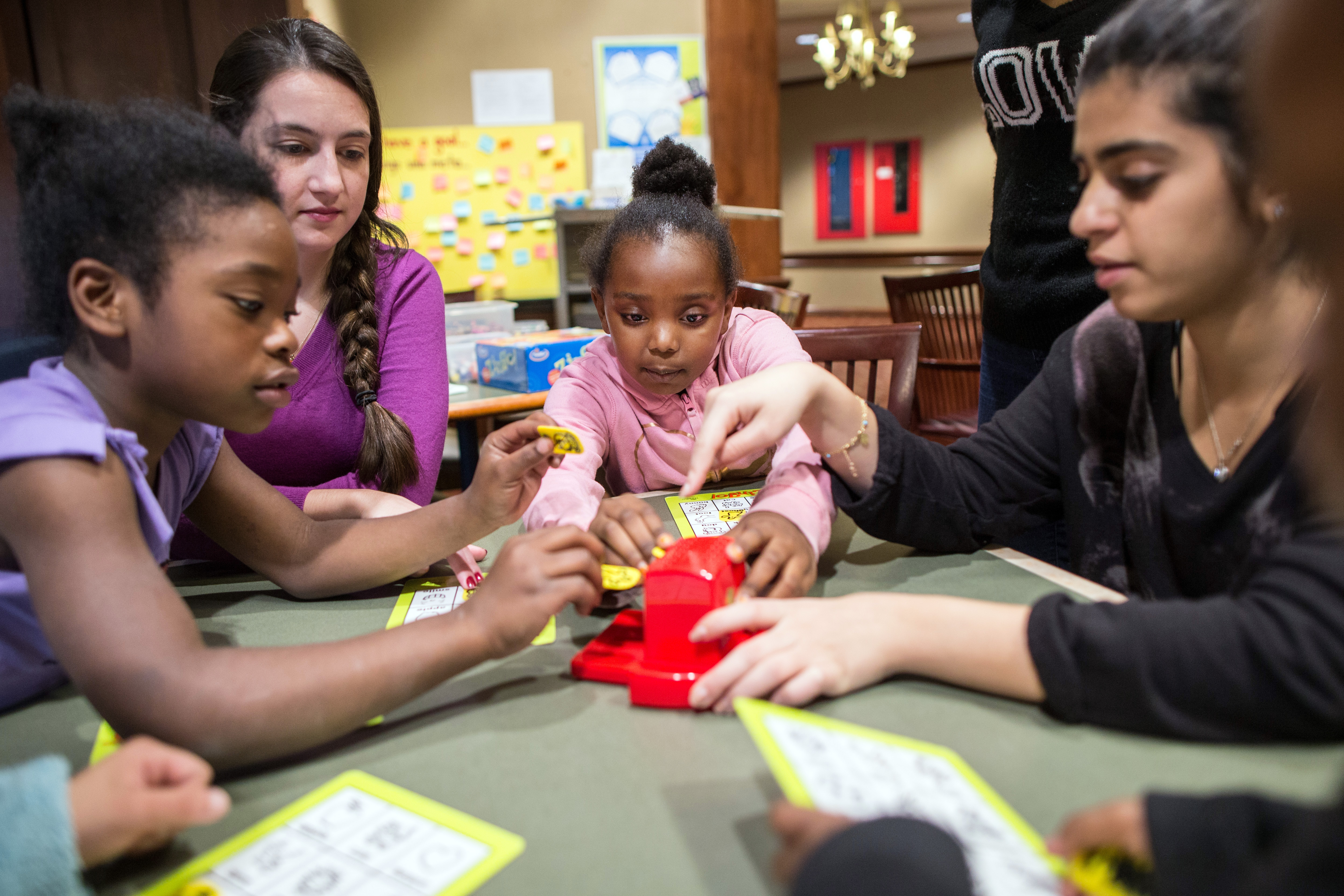 Jaliyah Rogers (center) joins a game with tutors Kendall Fawcett (second from left) and Maram Alarayedh at a Waltham hotel.