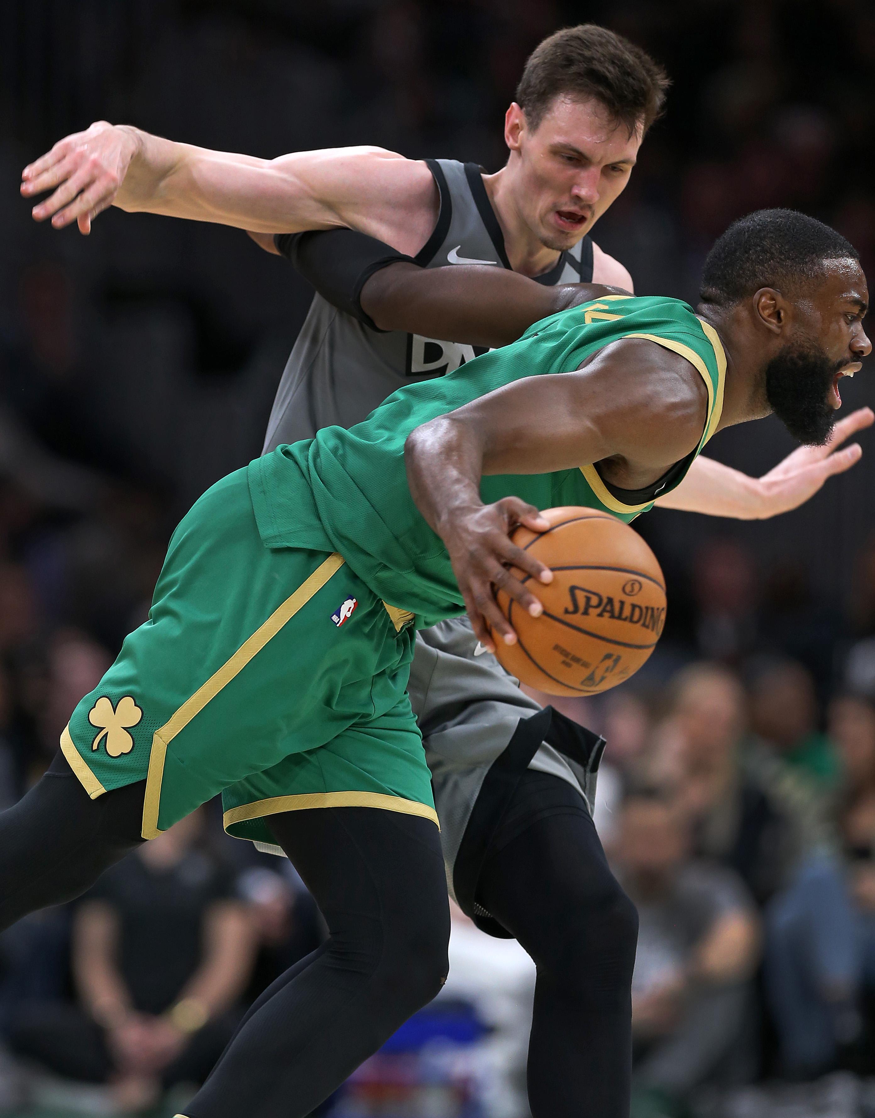 Jaylen Brown (front) gets tangled with the Nets’ Rodions Kurucs as he gains control of a loose ball in the first half.