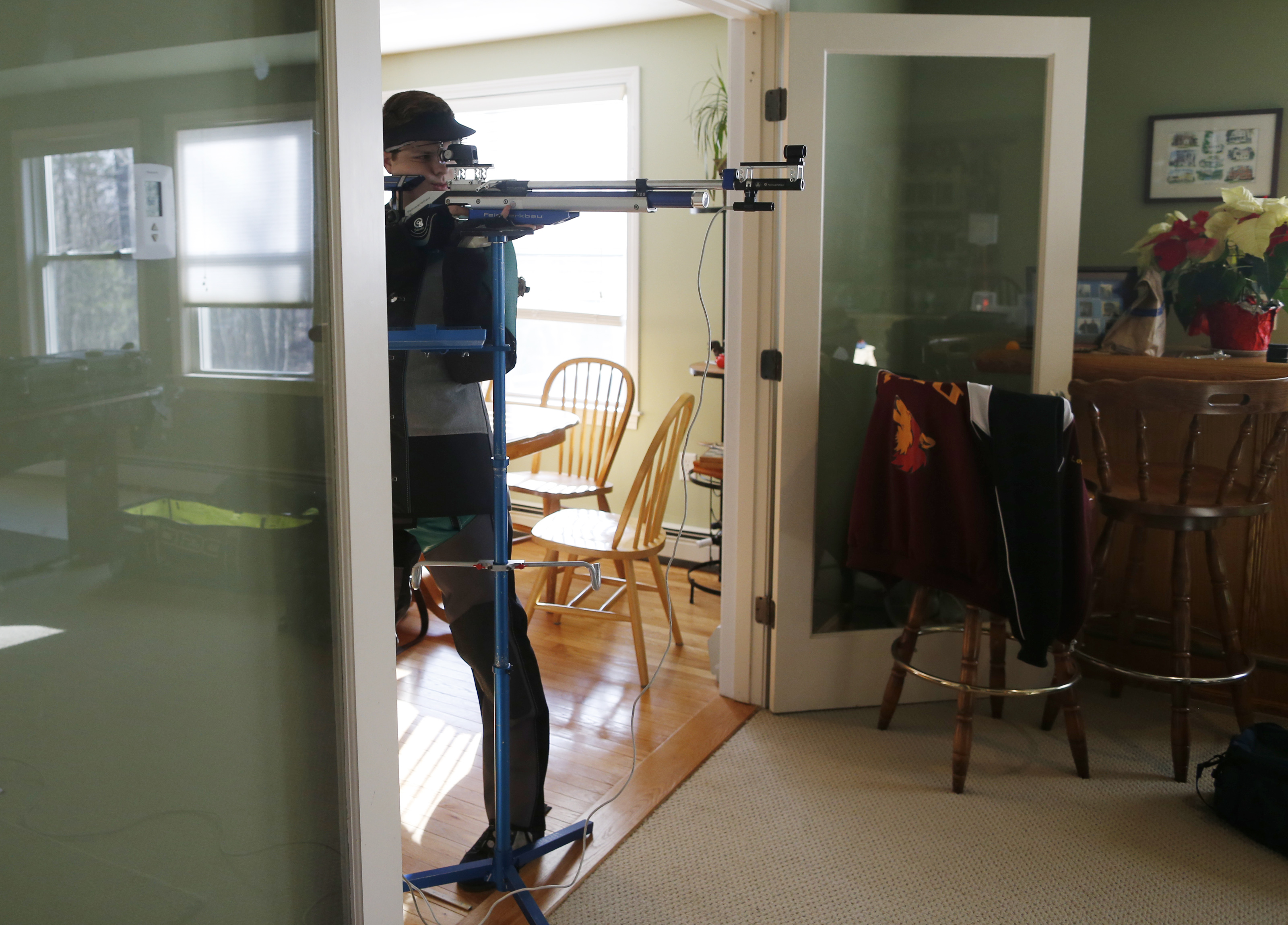Tyler Lefebvre, 17, a member of the Taunton Marksmanship Unit, practiced shooting with an air rifle in the living room of his home in Uxbridge, Mass.